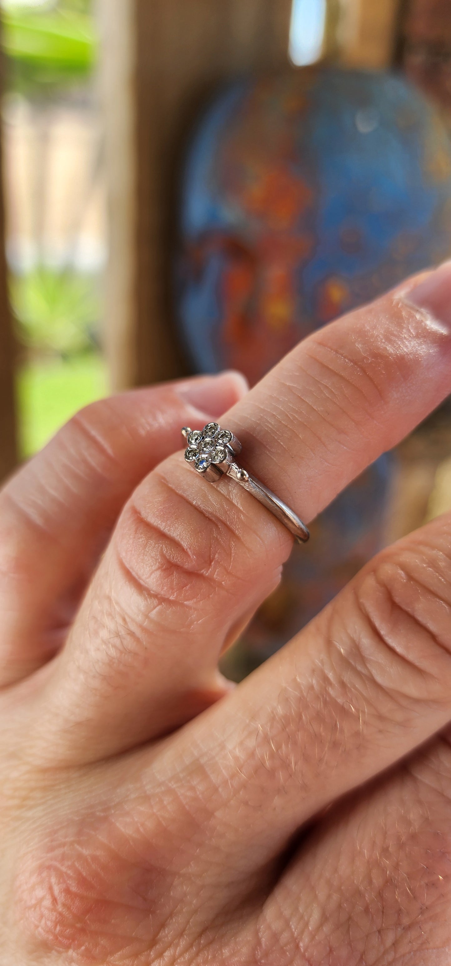 A timeless bloom of elegance—this vintage beauty is the epitome of delicate grace. Crafted in solid 18ct white gold, this charming ring features a petite flower cluster formed from seven small round cut white diamonds .
