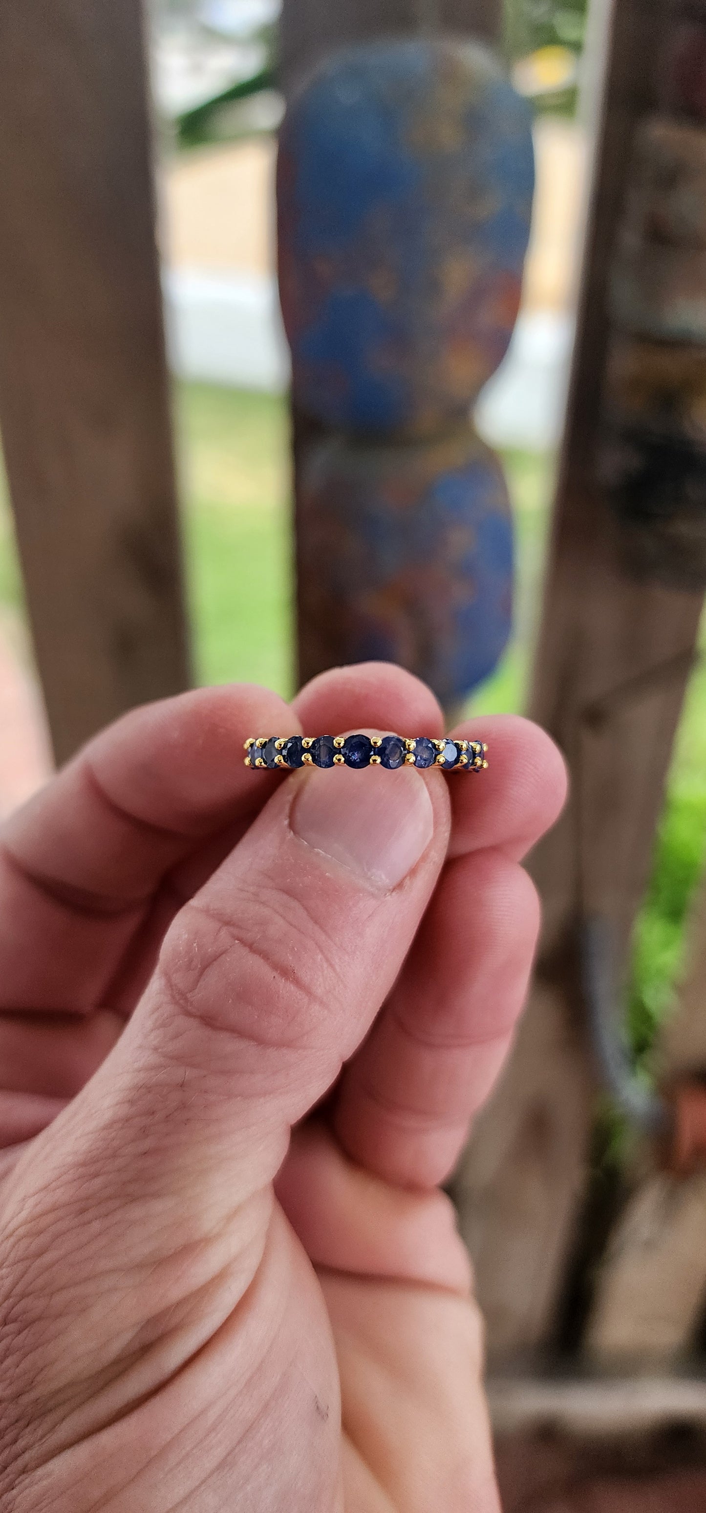 This unisex full eternity ring is masterfully forged in sterling silver and luxuriously plated in radiant yellow gold — a regal frame for 23 dazzling round-cut blue sapphires that shimmer like stars circling a golden sun.