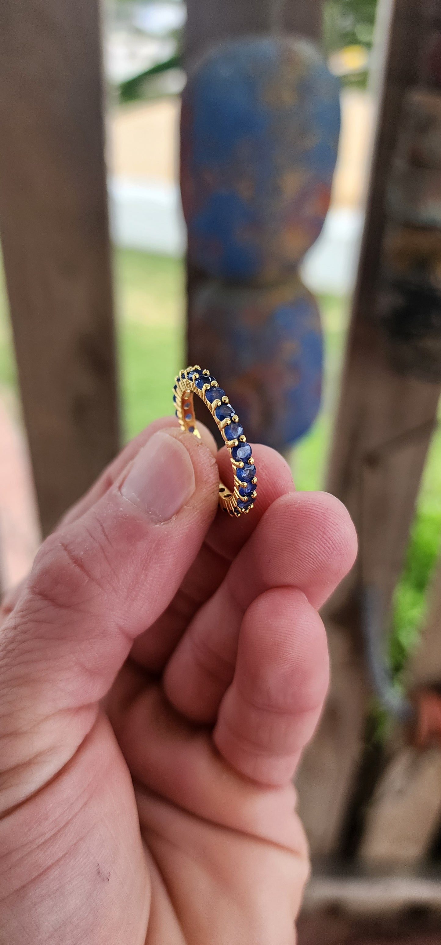 This unisex full eternity ring is masterfully forged in sterling silver and luxuriously plated in radiant yellow gold — a regal frame for 23 dazzling round-cut blue sapphires that shimmer like stars circling a golden sun.