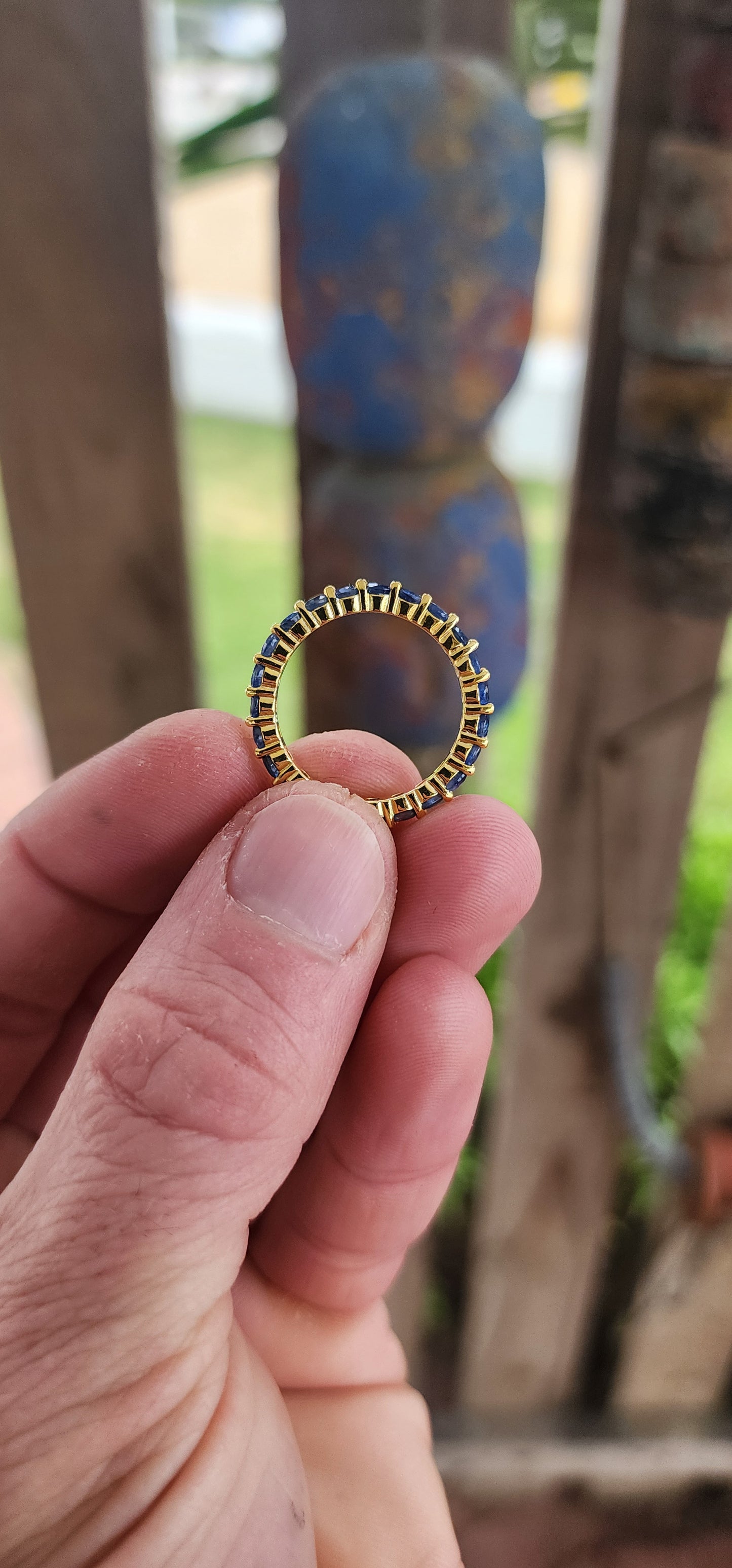 This unisex full eternity ring is masterfully forged in sterling silver and luxuriously plated in radiant yellow gold — a regal frame for 23 dazzling round-cut blue sapphires that shimmer like stars circling a golden sun.