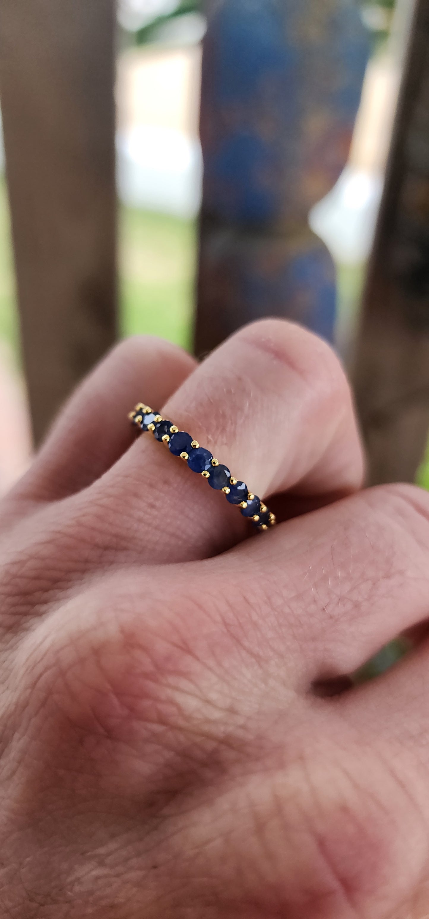 This unisex full eternity ring is masterfully forged in sterling silver and luxuriously plated in radiant yellow gold — a regal frame for 23 dazzling round-cut blue sapphires that shimmer like stars circling a golden sun.