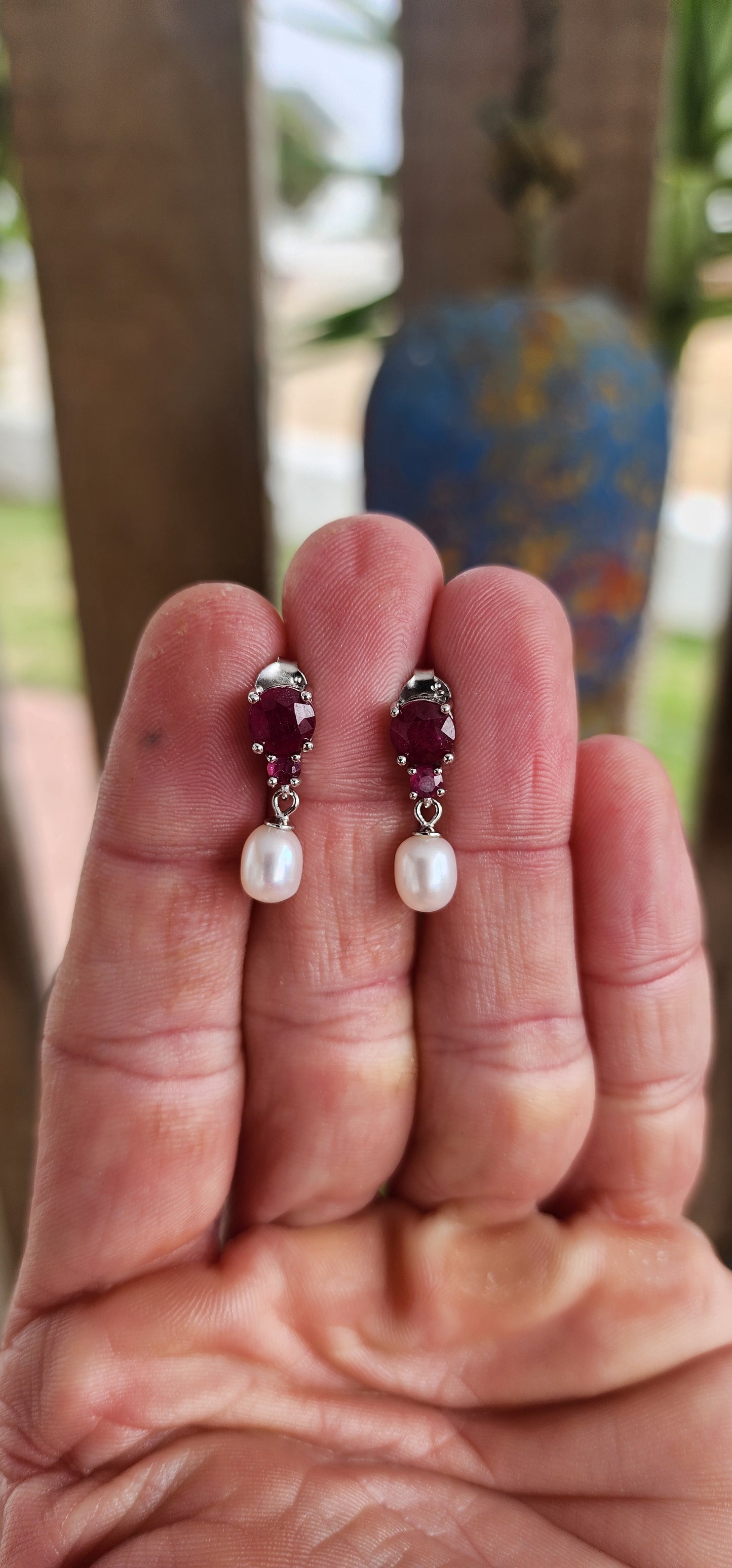 These radiant sterling silver earrings are a celebration of timeless romance .At their crown, each earring features a round-cut ruby in a rich, velvety crimson hue—expertly prong-set to capture and dance with the light like a spark from a royal hearth.