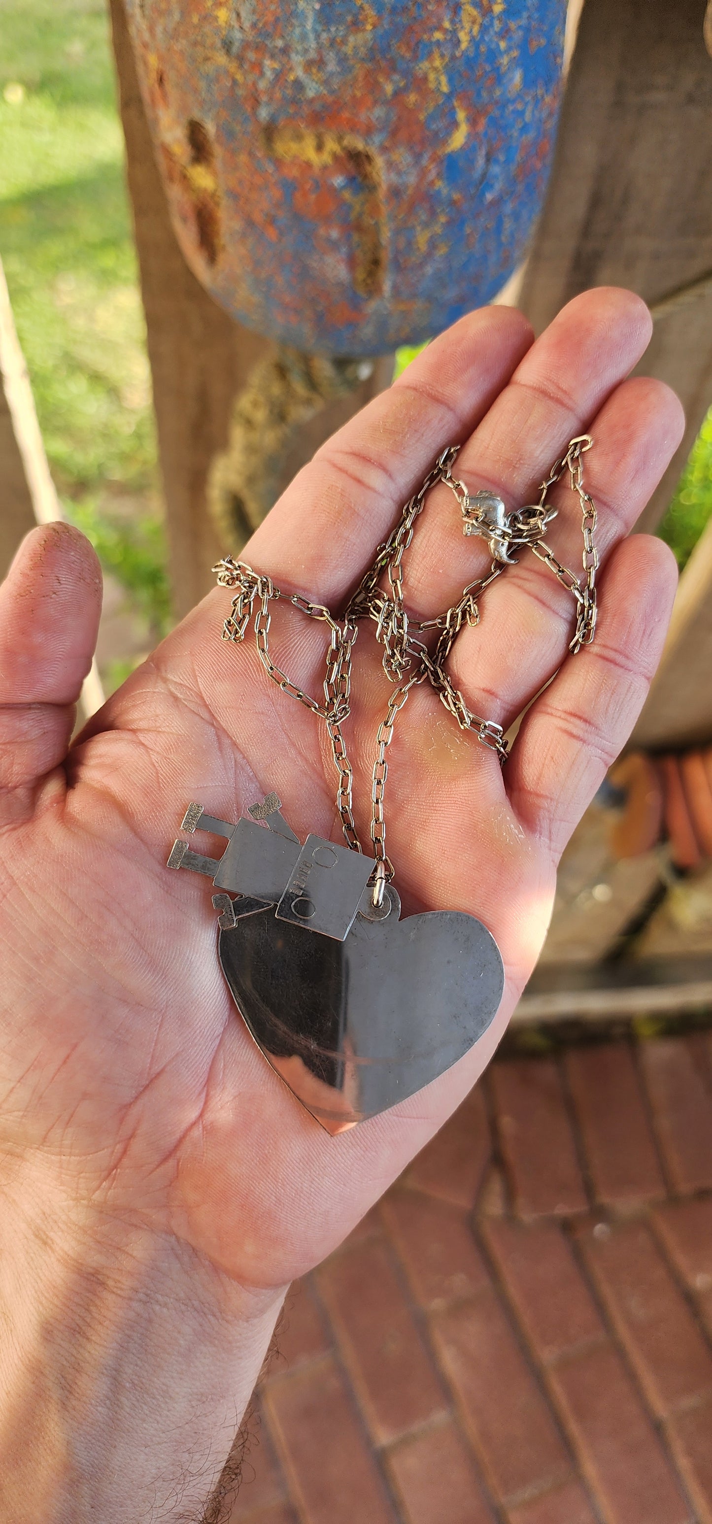 This necklace is pure quirky charm meets retro-futuristic flair!
Crafted in sterling silver, this artisan-made, extra-length necklace features a playful pendant duo that’s sure to spark conversation wherever you go.