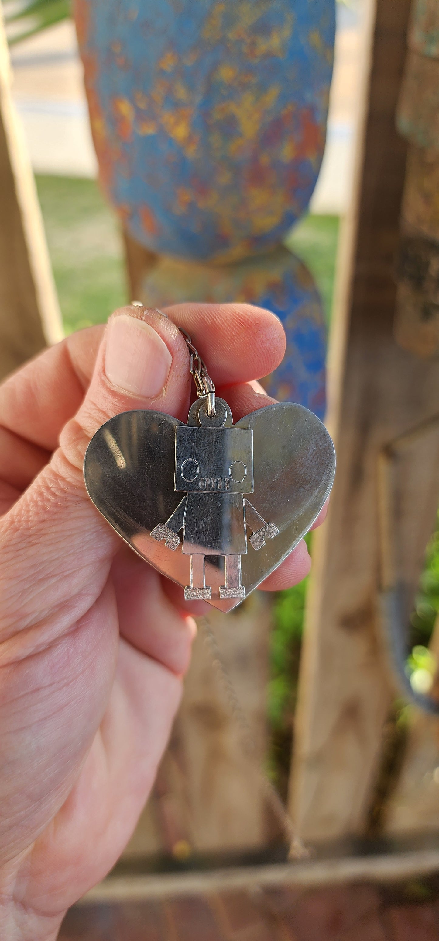 This necklace is pure quirky charm meets retro-futuristic flair!
Crafted in sterling silver, this artisan-made, extra-length necklace features a playful pendant duo that’s sure to spark conversation wherever you go.