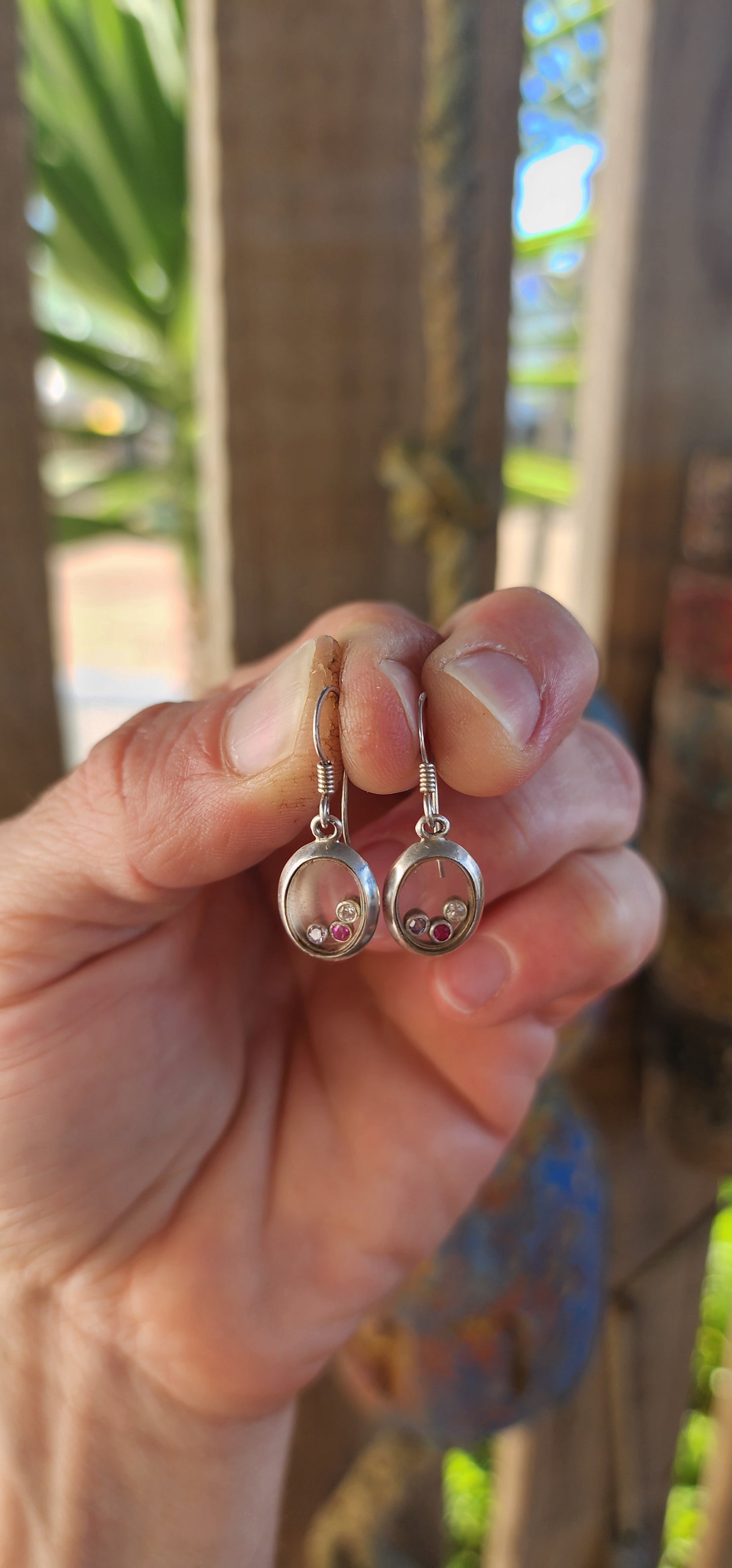 Ready to add a dash of whimsy to your lobes? These charming sterling silver drop earrings are like miniature curiosity cabinets for your ears — each one an oval-shaped porthole with a secret sparkling surprise inside.