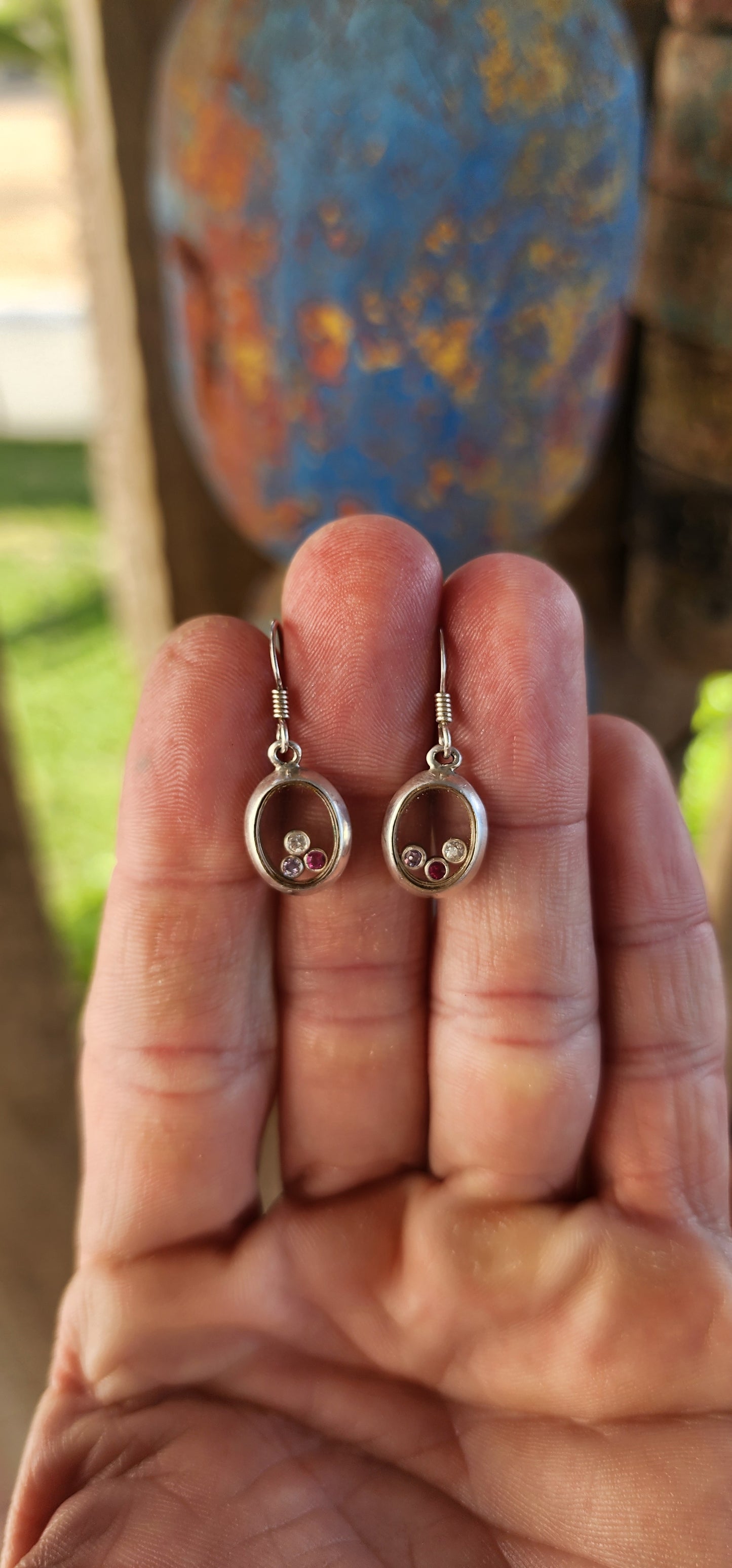 Ready to add a dash of whimsy to your lobes? These charming sterling silver drop earrings are like miniature curiosity cabinets for your ears — each one an oval-shaped porthole with a secret sparkling surprise inside.