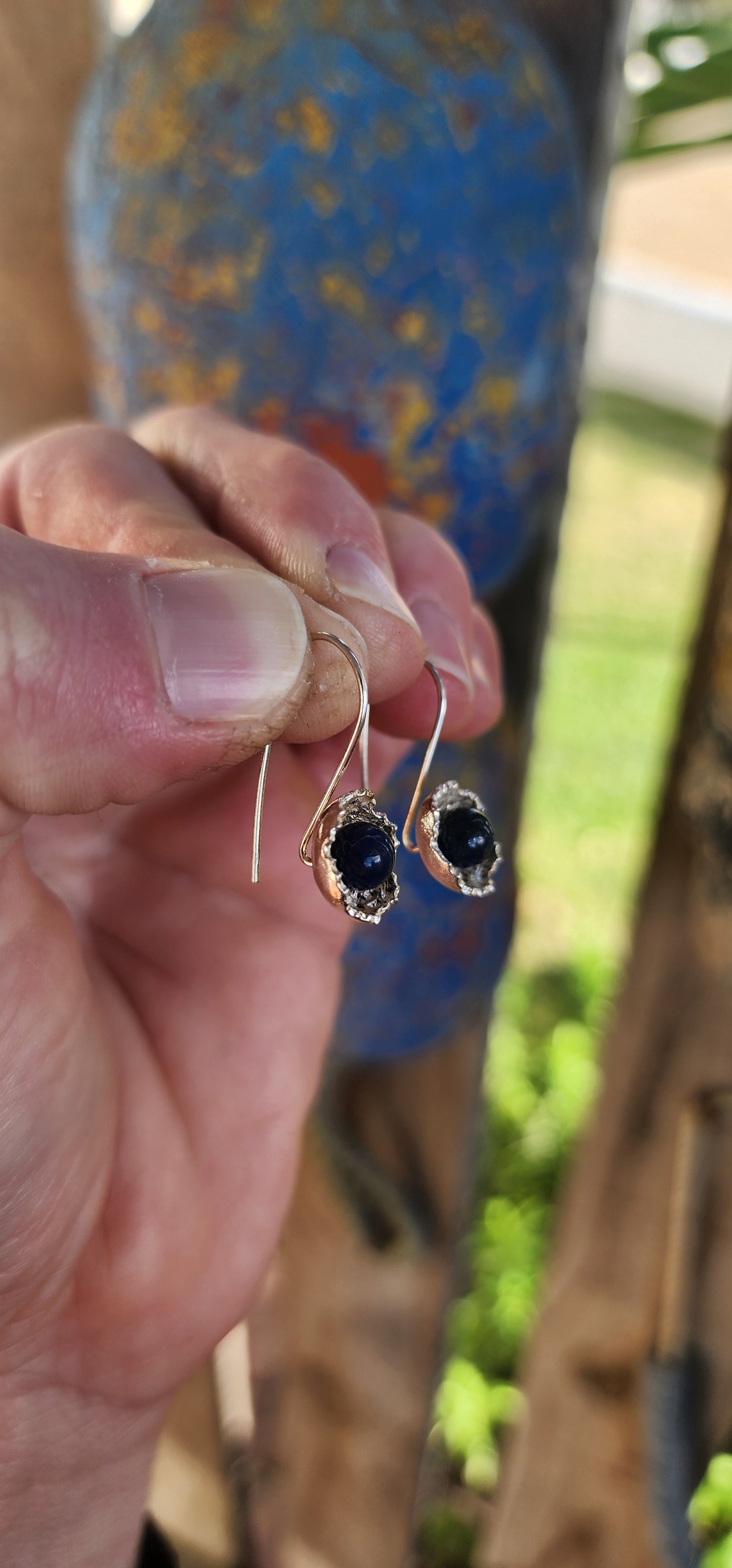 Artisan-crafted sterling silver drop earrings, each one features a richly textured, organic floral cup cradling a perfectly polished orb of deep royal blue lapis lazuli.
The lapis gleams with its signature golden flecks of pyrite.