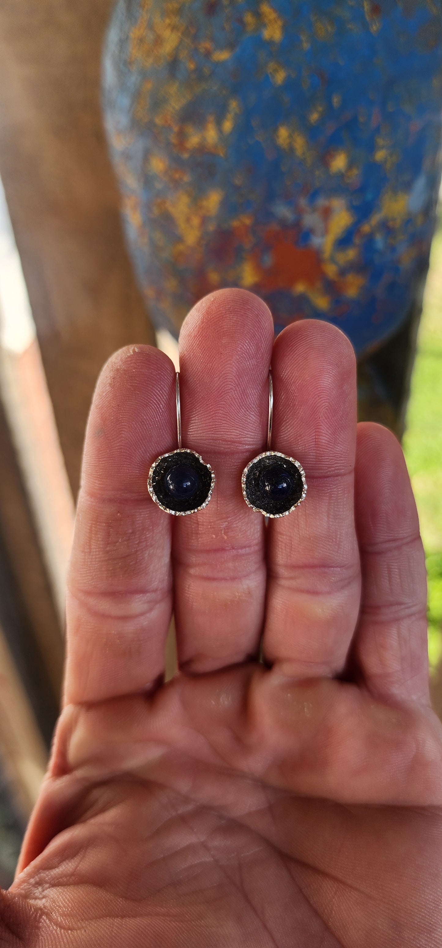Artisan-crafted sterling silver drop earrings, each one features a richly textured, organic floral cup cradling a perfectly polished orb of deep royal blue lapis lazuli.
The lapis gleams with its signature golden flecks of pyrite.