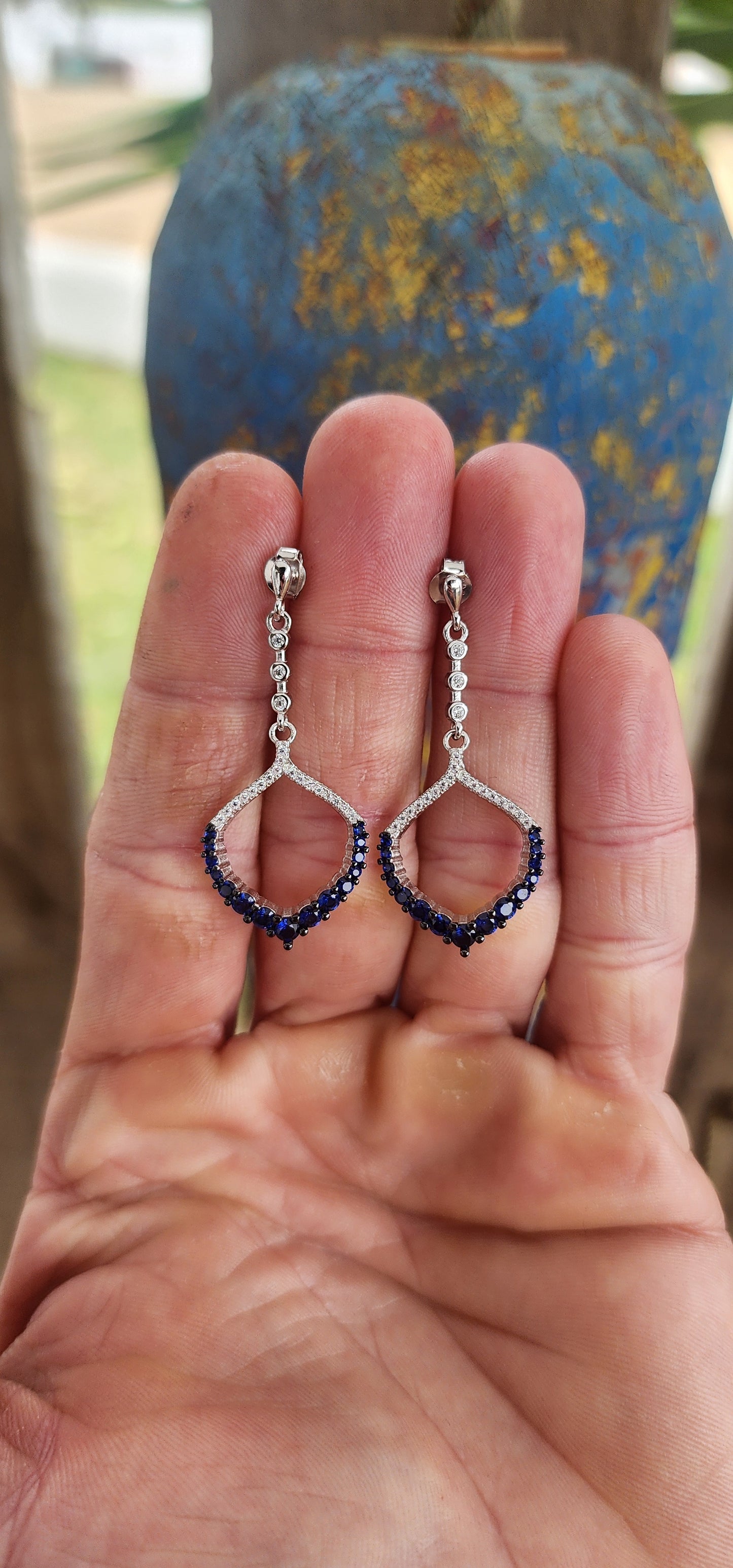 These dazzling drop earrings are where playful charm meets red carpet drama. Crafted in sleek, polished sterling silver, they feature an elegant vertical line of bezel-set clear round-cut cubic zirconia (CZ) gemstones, creating a graceful trail of sparkle