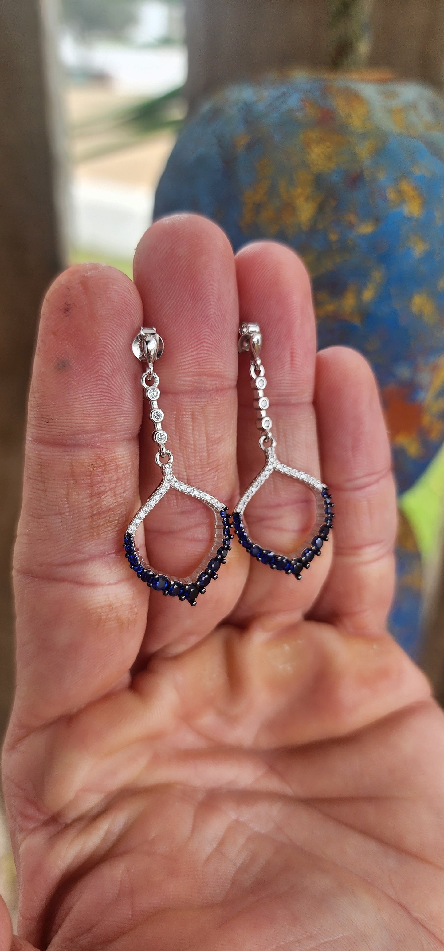 These dazzling drop earrings are where playful charm meets red carpet drama. Crafted in sleek, polished sterling silver, they feature an elegant vertical line of bezel-set clear round-cut cubic zirconia (CZ) gemstones, creating a graceful trail of sparkle