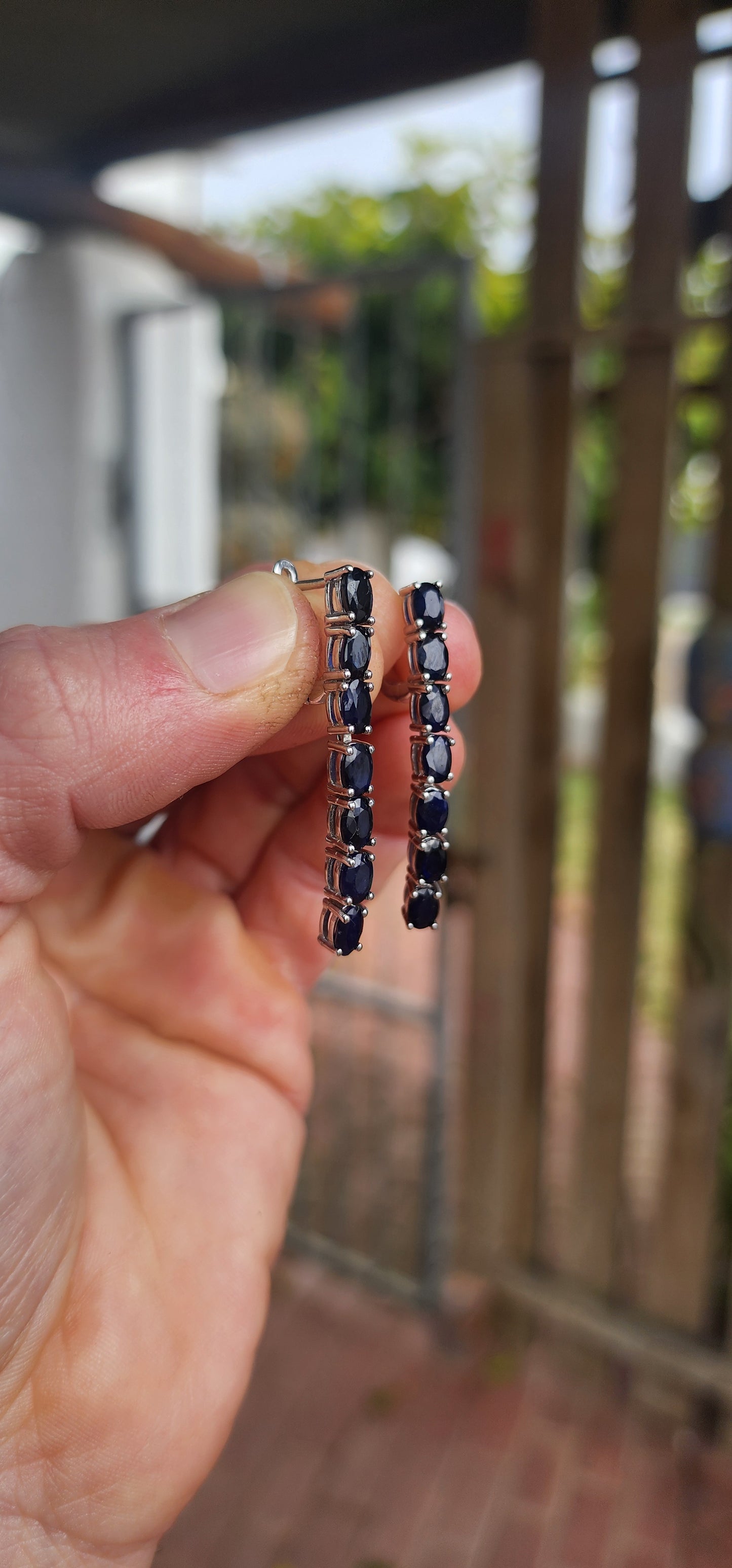 These sterling silver dangle earrings are designed to showcase the mysterious beauty of deep blue sapphires.