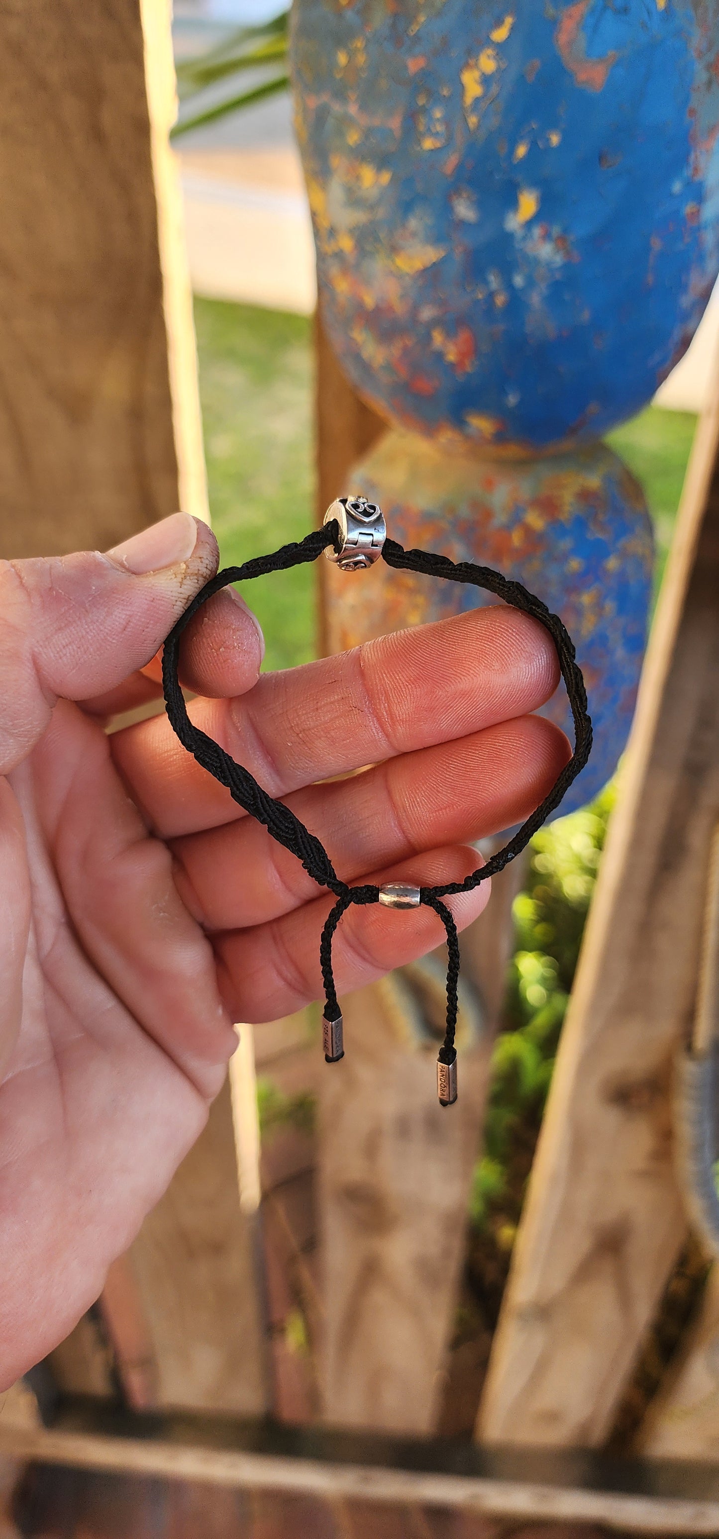 This stylish unisex P-a-n-d-o-r-a bracelet is a contemporary take on a timeless craft. Meticulously woven in rich black macramé cord, the bracelet showcases a robust and flexible structure, designed to adapt comfortably to a variety of wrist sizes.