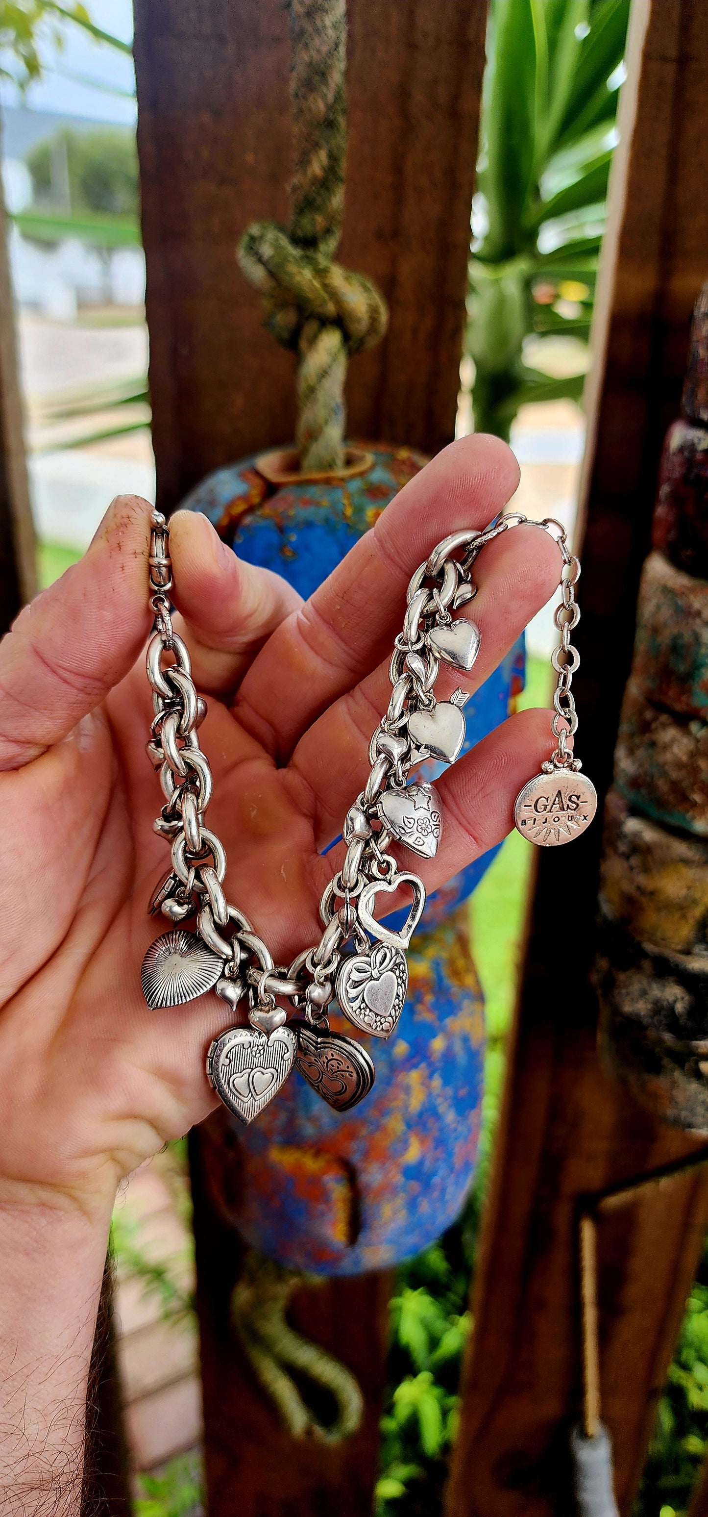 Exquisite designer costume charm bracelet by the celebrated French house Gas Bijoux. Crafted with a substantial silver-plated oval-link chain, this bracelet is a joyful celebration of love, nostalgia, and bohemian spirit.