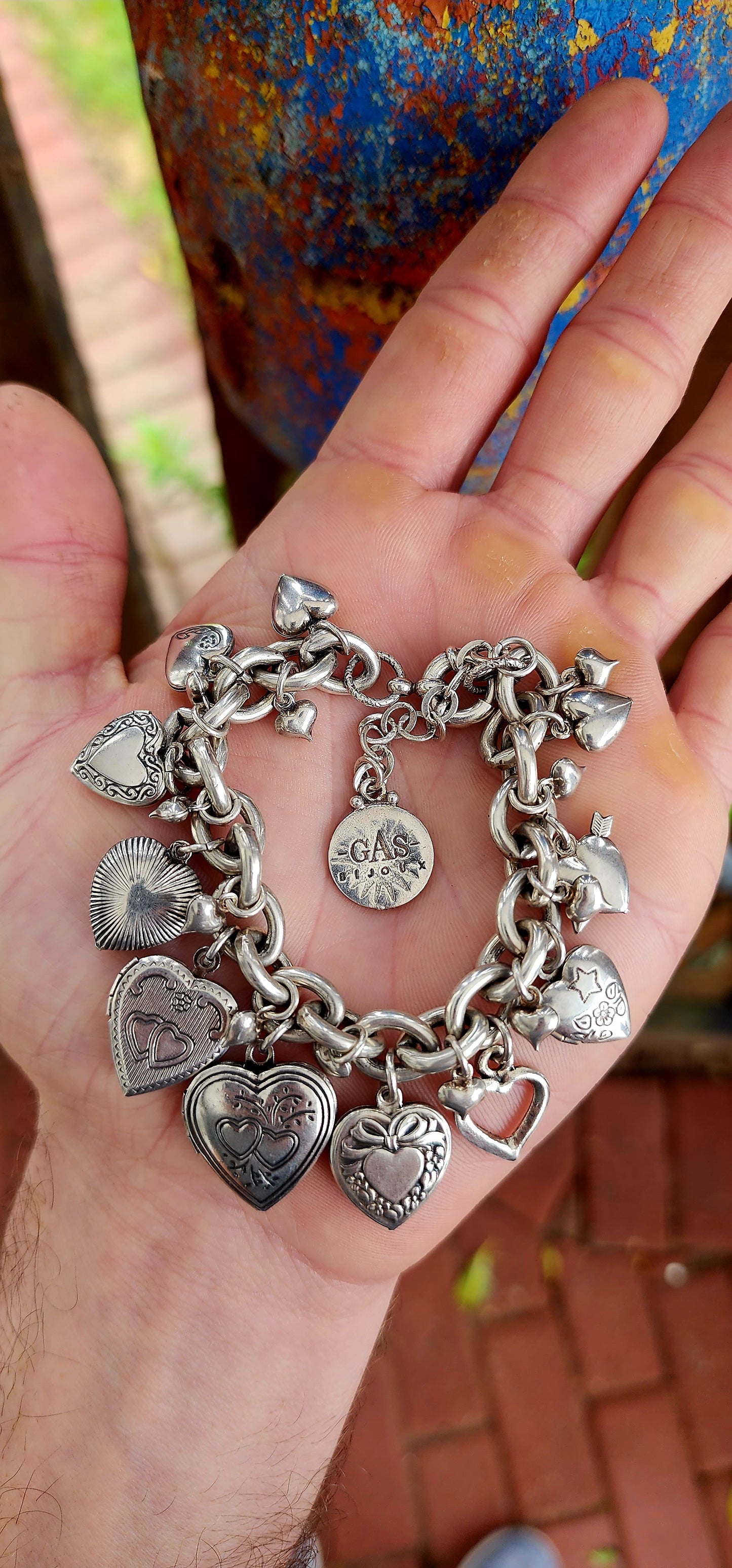 Exquisite designer costume charm bracelet by the celebrated French house Gas Bijoux. Crafted with a substantial silver-plated oval-link chain, this bracelet is a joyful celebration of love, nostalgia, and bohemian spirit.