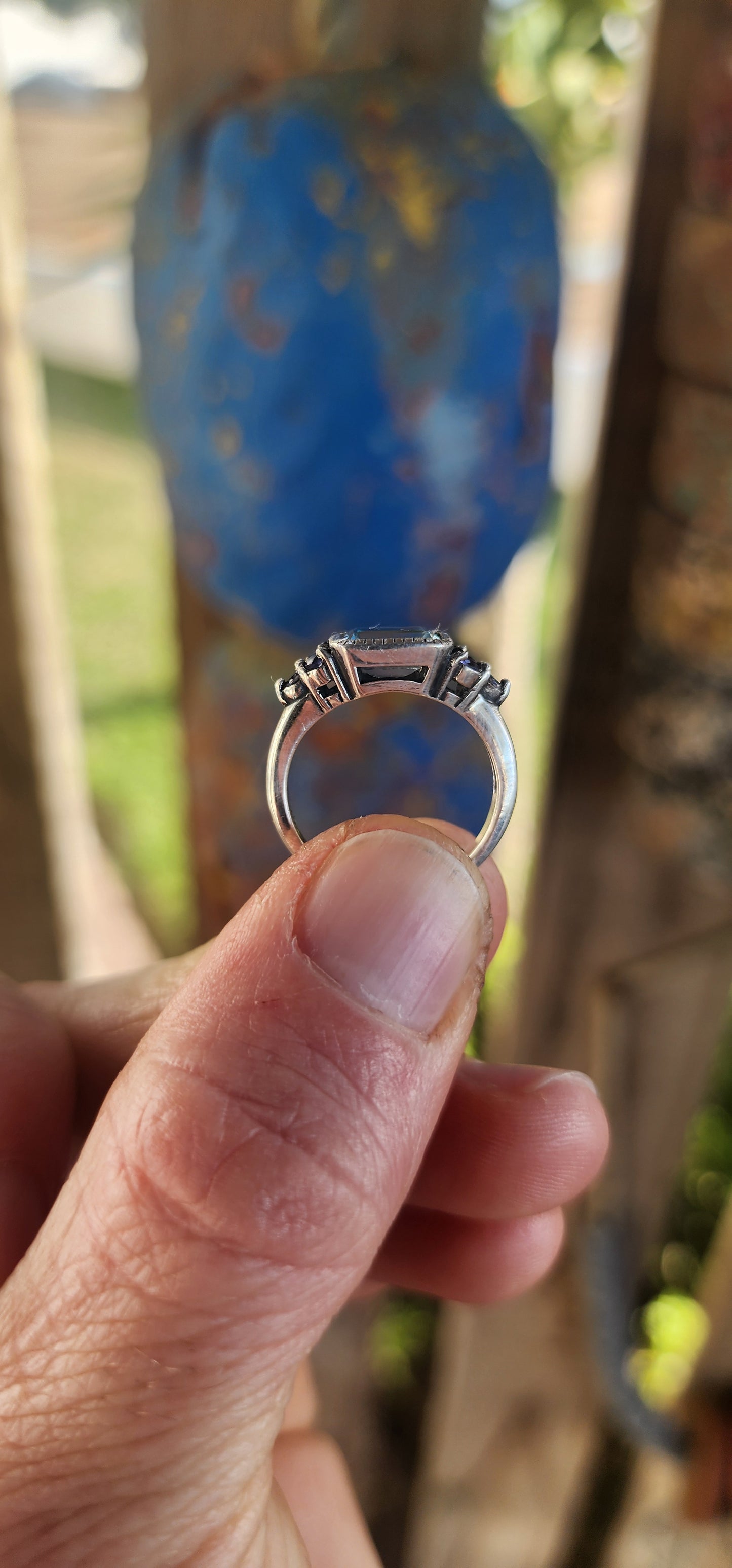 A delicate balance of clarity, color, and craftsmanship, this elegant trilogy-style stacking ring is crafted in sterling silver. At its heart lies a captivating emerald-cut sky blue topaz, its crystalline hue as refreshing as a cloudless morning sky.