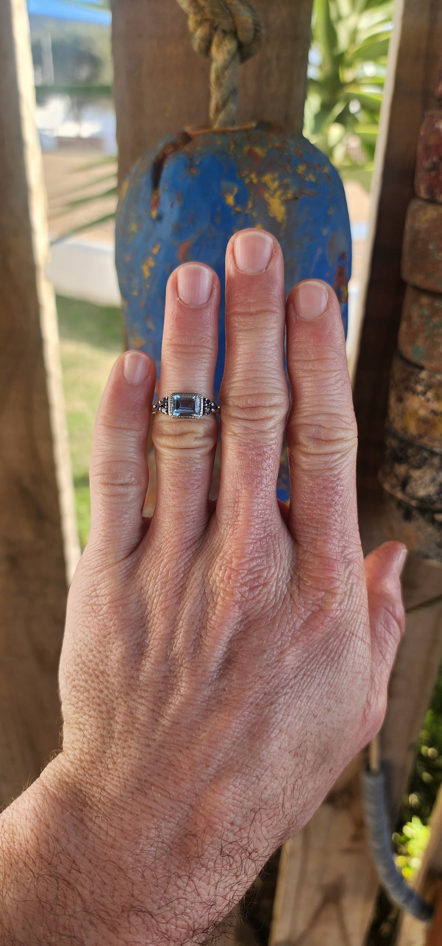 A delicate balance of clarity, color, and craftsmanship, this elegant trilogy-style stacking ring is crafted in sterling silver. At its heart lies a captivating emerald-cut sky blue topaz, its crystalline hue as refreshing as a cloudless morning sky.