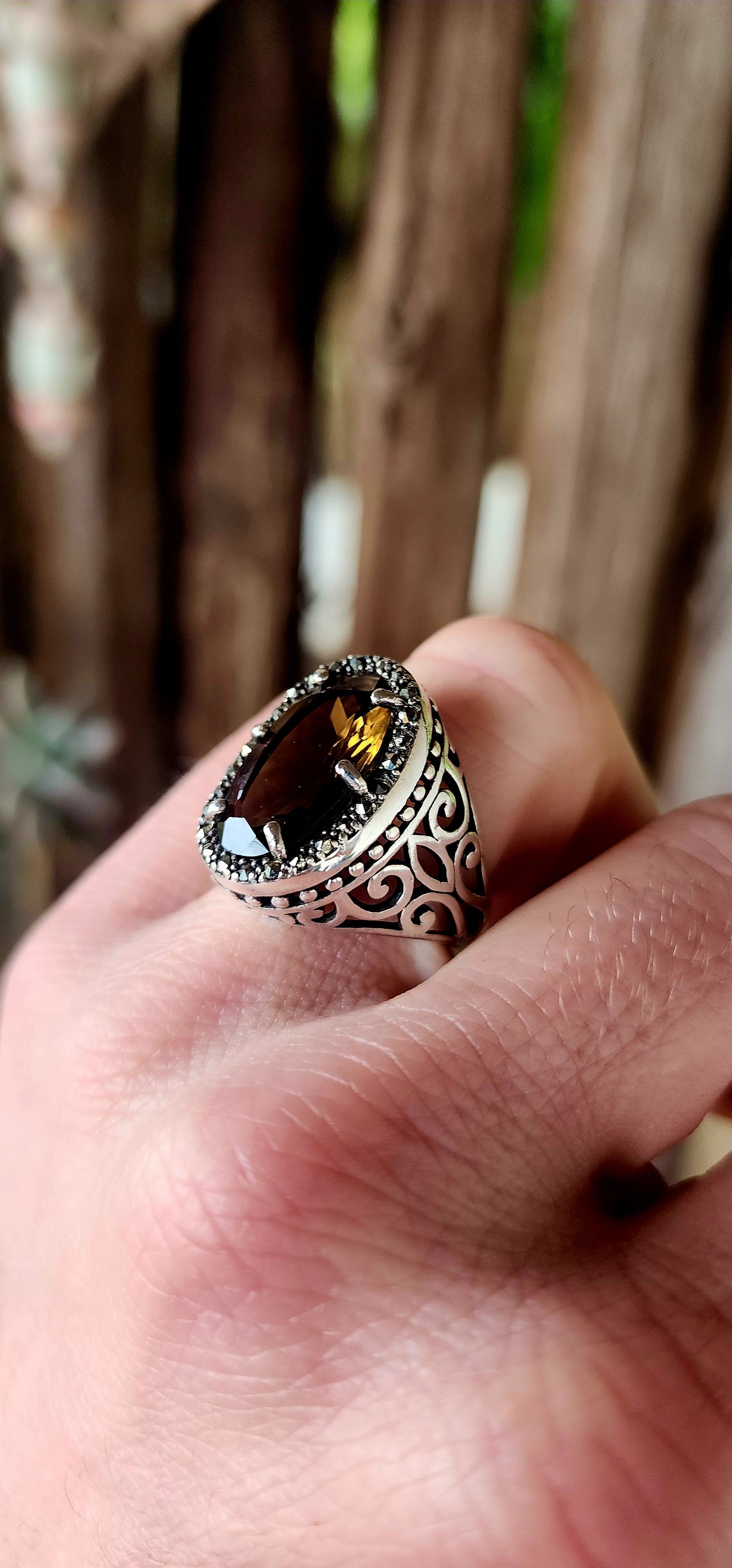 This bold and beautifully crafted sterling silver cocktail ring channels the grandeur of antique jewelry design. At its heart lies a large and rare oval-cut champagne/brown topaz.