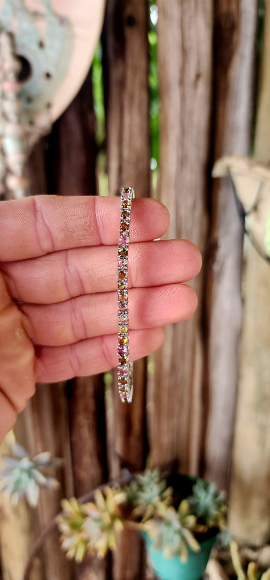 Meet the bracelet that refuses to pick a favorite color! This sleek sterling silver tennis-style beauty lines up 43 round-cut tourmaline gemstones in a dazzling spectrum—from leafy greens and golden ambers to bubblegum pinks and raspberry reds.