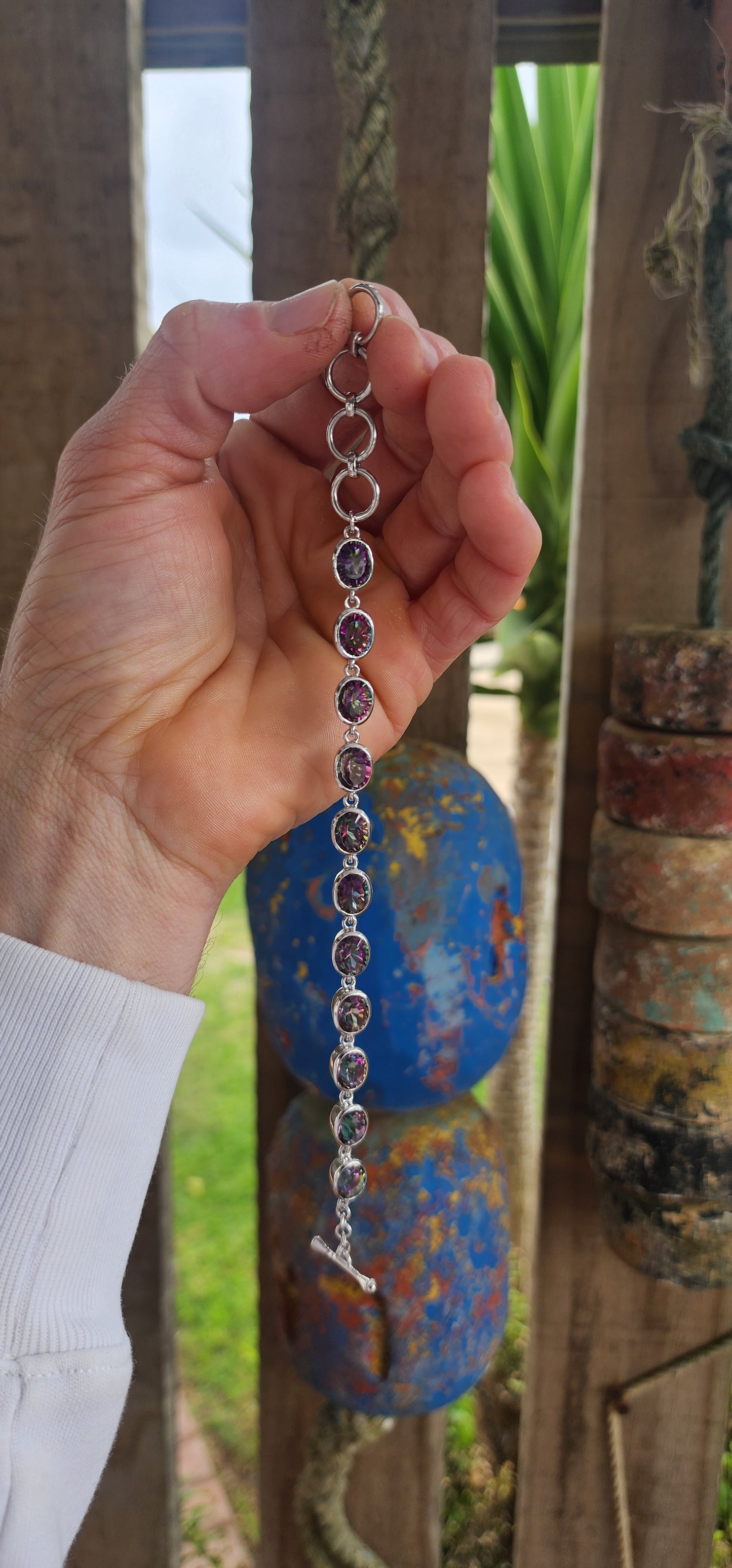 This striking bracelet is crafted in sterling silver in a classic tennis-style design, giving it both elegance and versatility. It features a continuous lineup of 11 generously sized oval-cut Mystic Topaz gemstones.