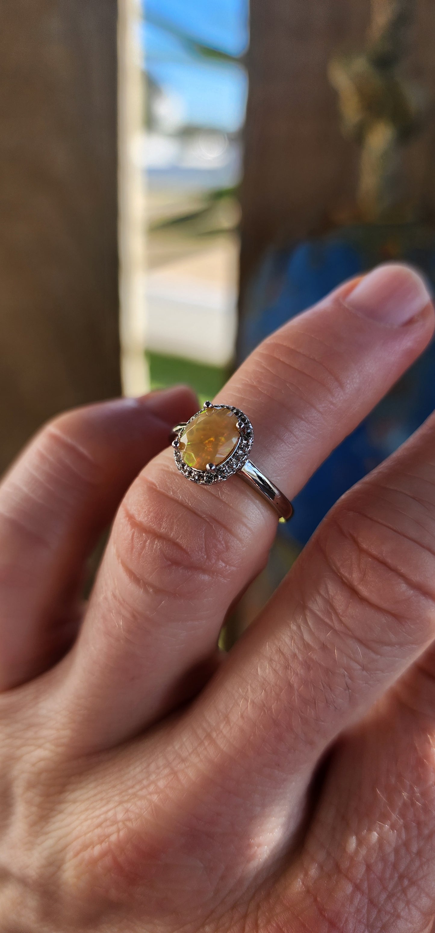 A timeless classic with a magical twist! This sterling silver beauty showcases a glowing orange oval-cut Ethiopian opal, prong set at the center where it shimmers with fiery flashes of orange, green, and golden yellow – like a sunset captured in stone.