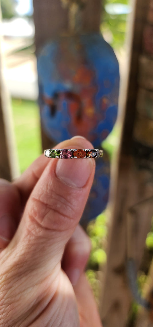 Let your fingers tell a story of color and wonder with this enchanting sterling silver half-eternity ring.