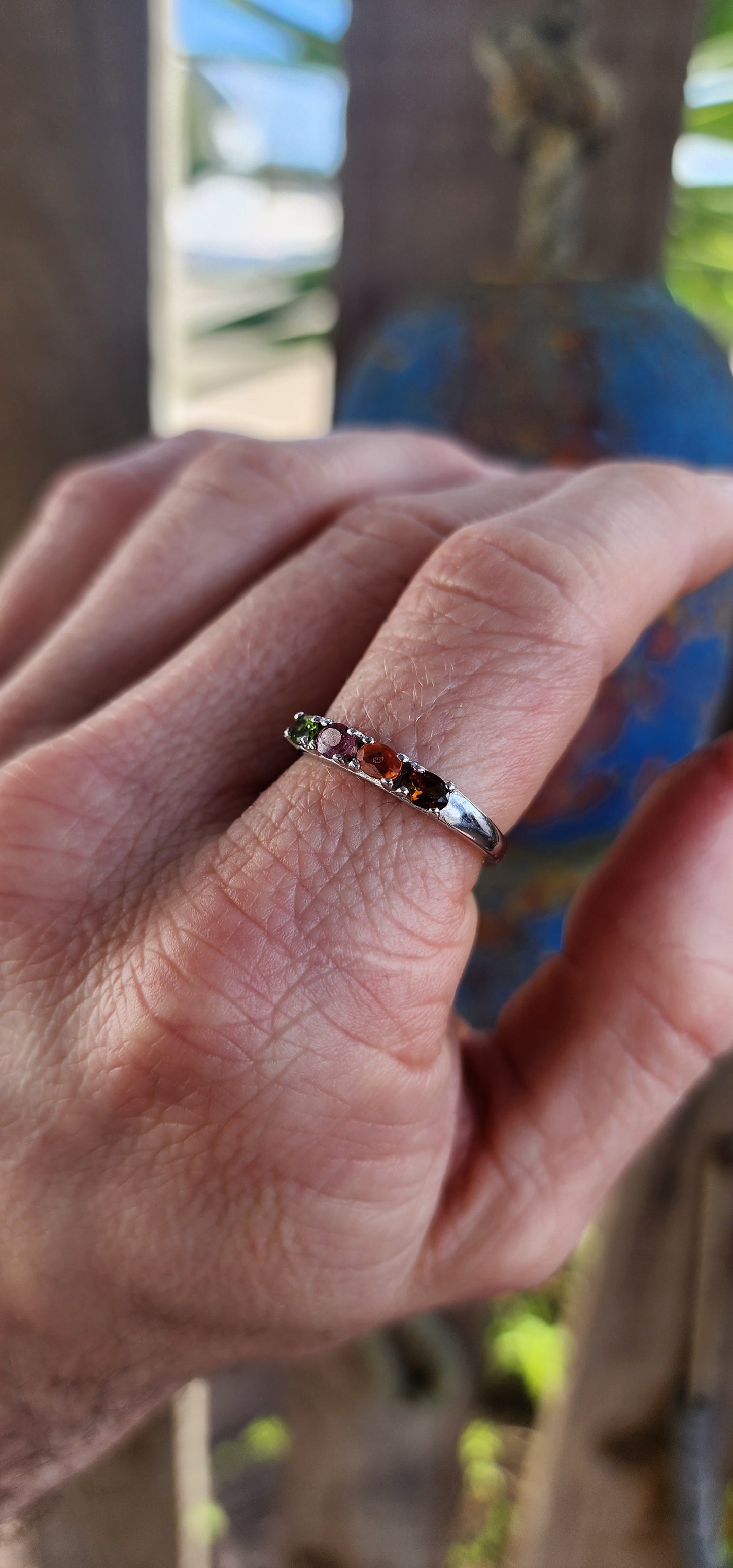 Let your fingers tell a story of color and wonder with this enchanting sterling silver half-eternity ring.