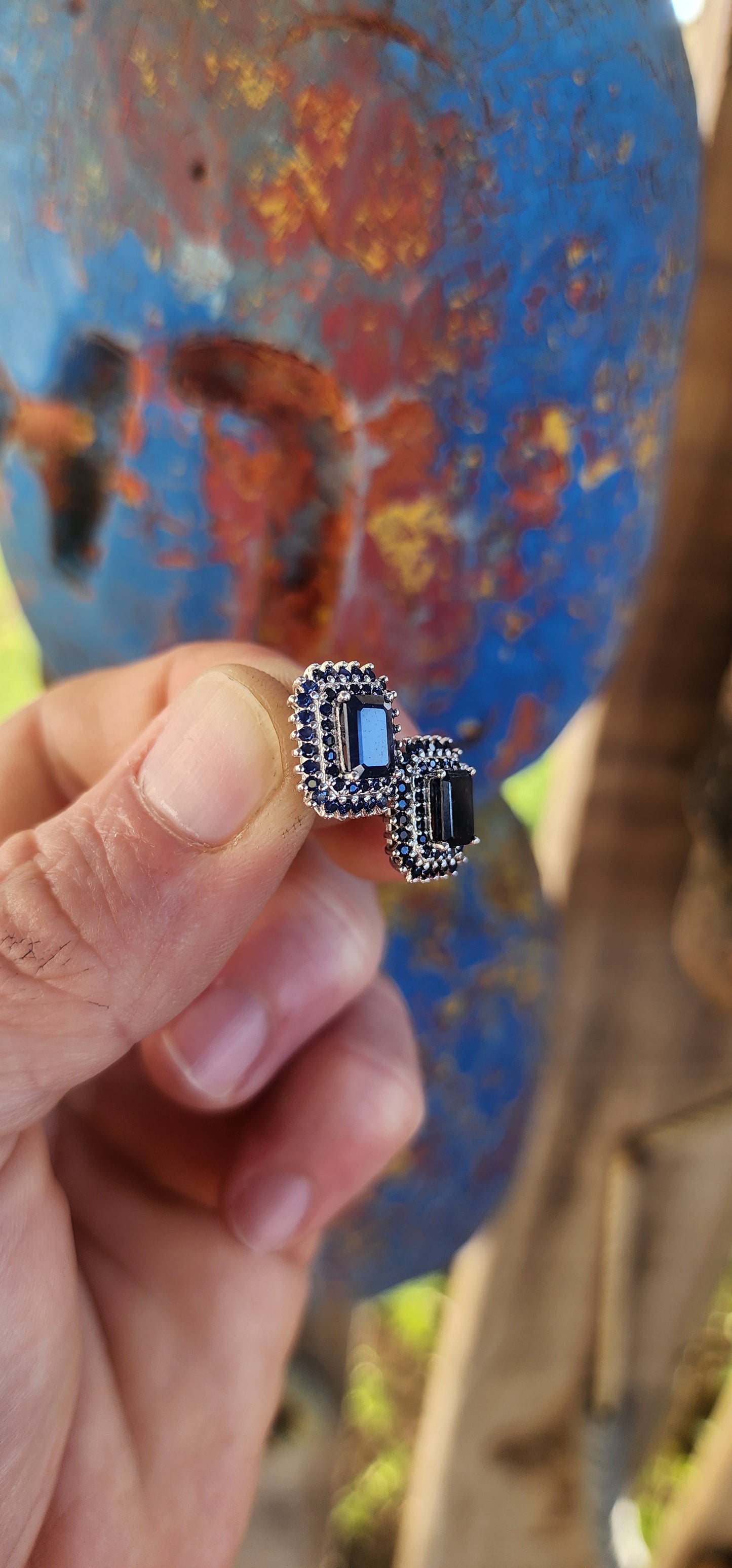 Striking and regal, these sterling silver stud earrings each feature a richly colored emerald-cut deep blue sapphire at the center.