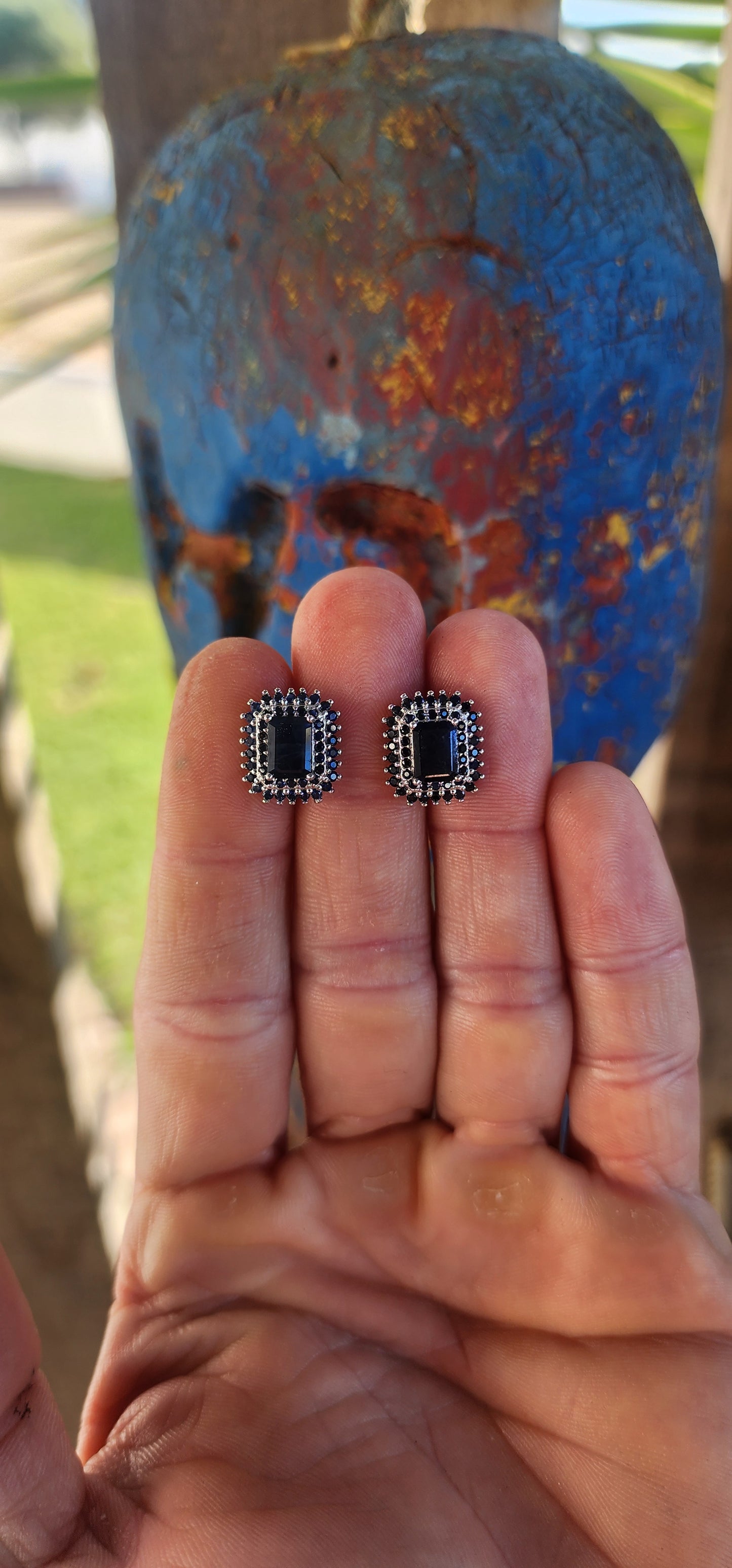 Striking and regal, these sterling silver stud earrings each feature a richly colored emerald-cut deep blue sapphire at the center.