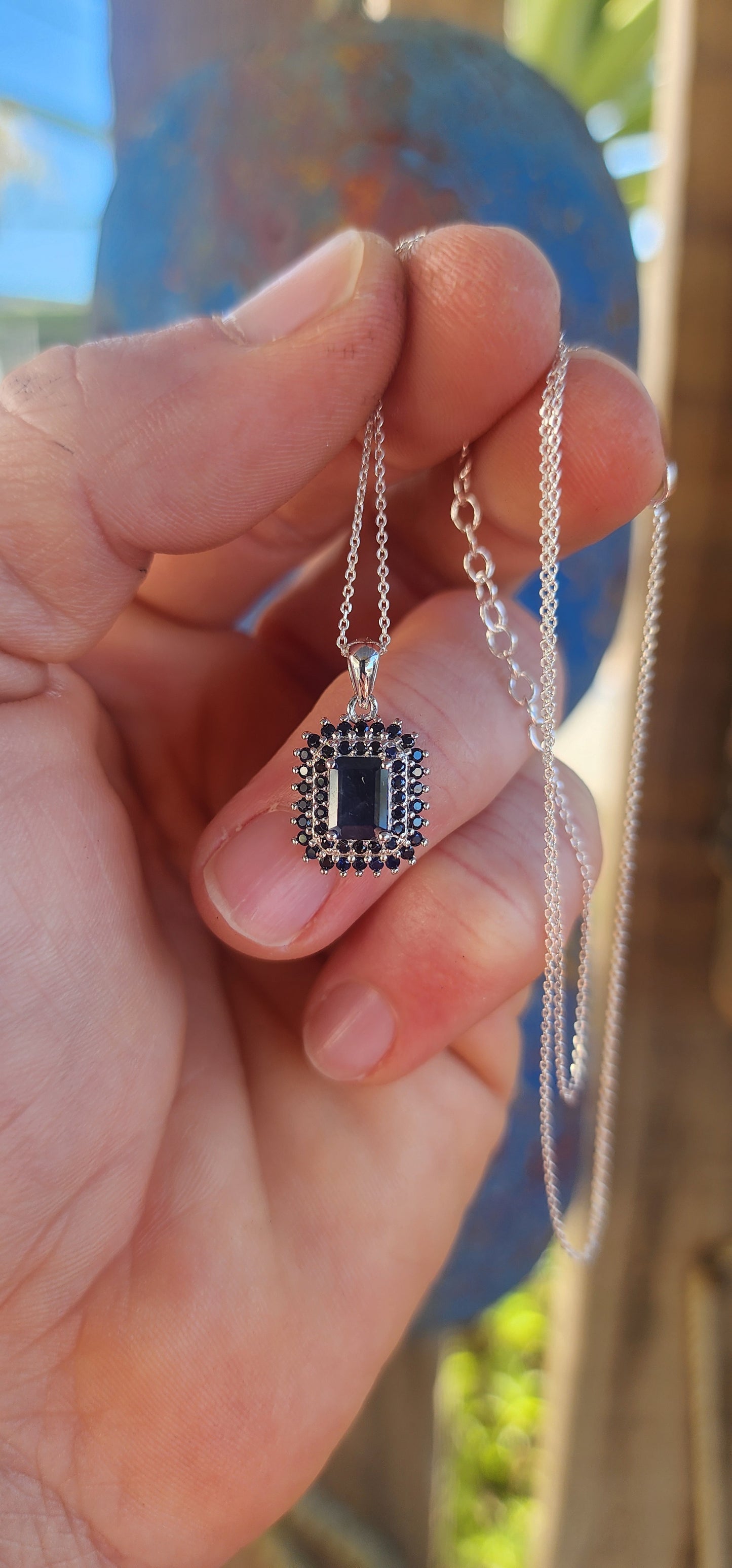 Elegant and timeless, this pendant features a richly saturated emerald-cut deep blue sapphire as its centerpiece, prong-set to capture and reflect light with depth and intensity.