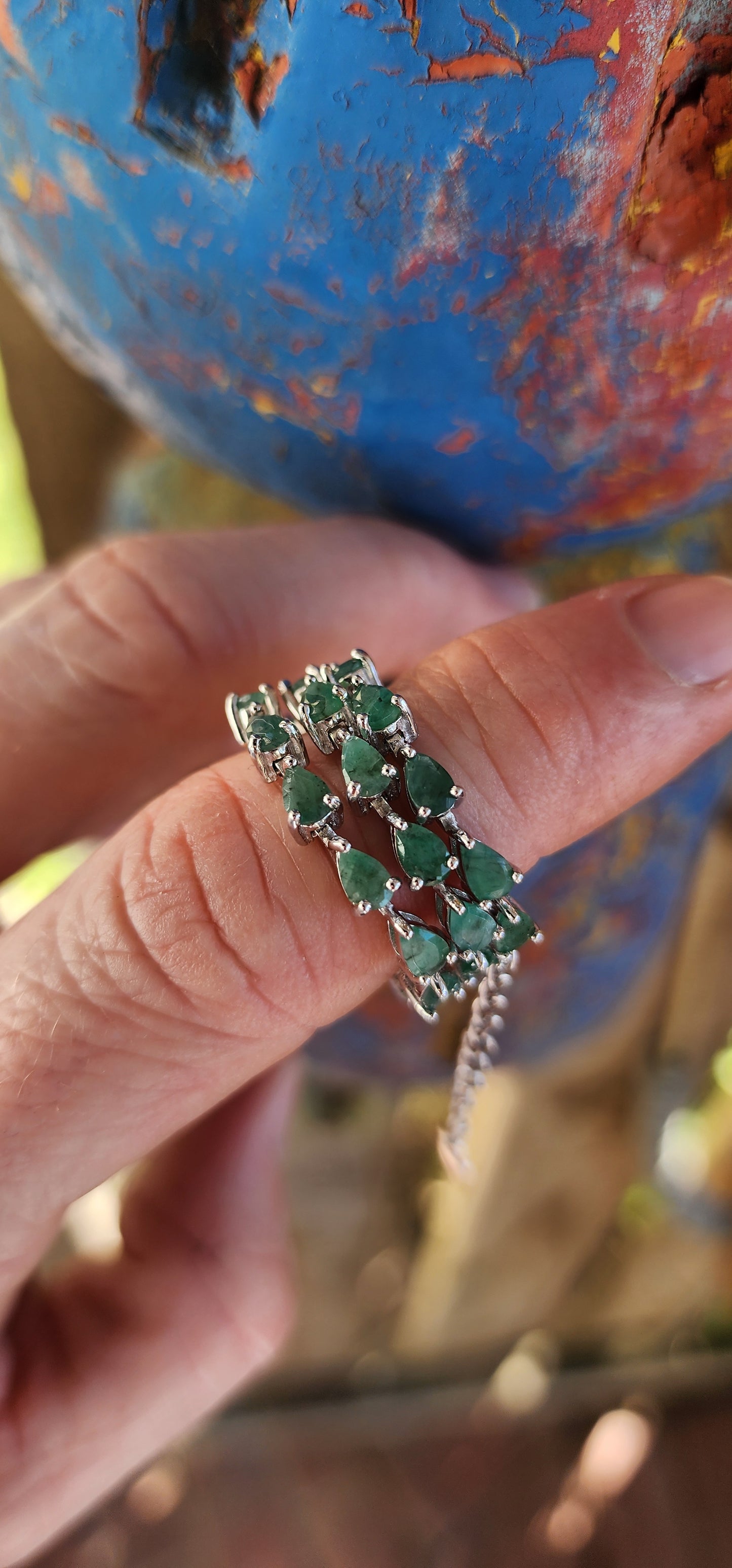 Up for grabs is this magnificent sterling silver unisex tennis bracelet, set with a striking line of 27 pear-cut emerald gemstones.