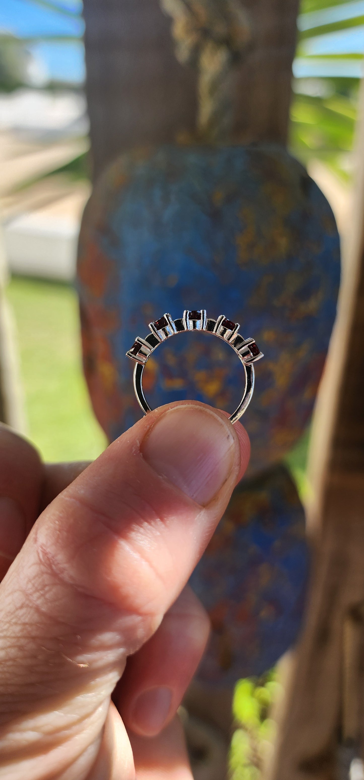 This sterling silver half-eternity ring is a timeless and elegant piece, featuring five richly hued oval-cut garnet gemstones.
