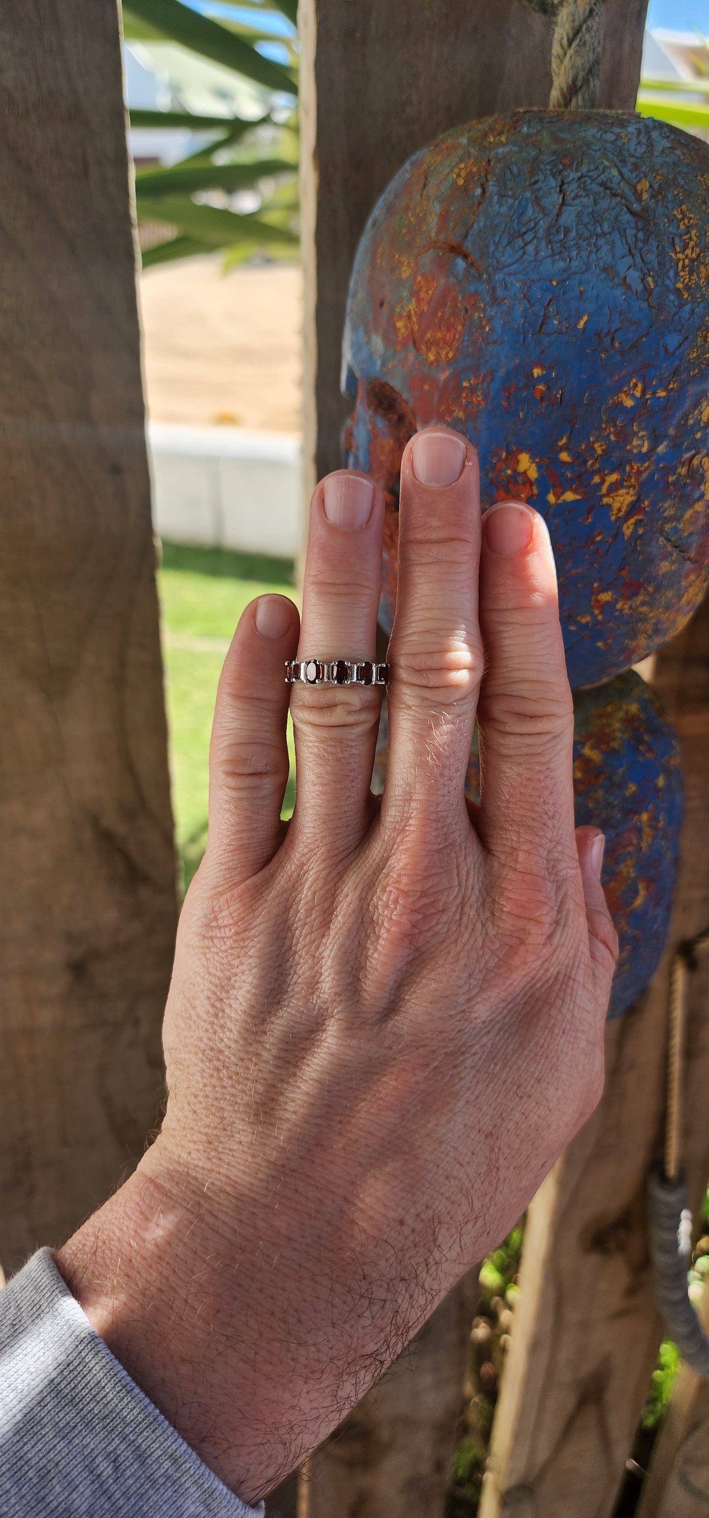 This sterling silver half-eternity ring is a timeless and elegant piece, featuring five richly hued oval-cut garnet gemstones.