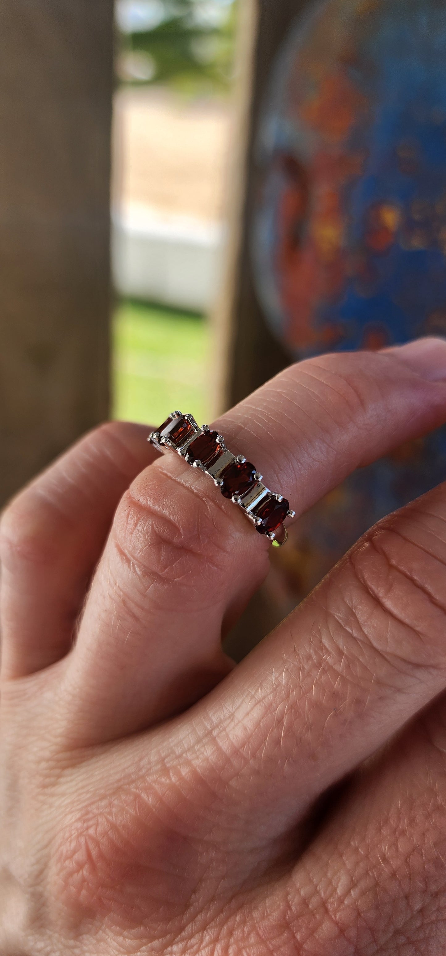This sterling silver half-eternity ring is a timeless and elegant piece, featuring five richly hued oval-cut garnet gemstones.