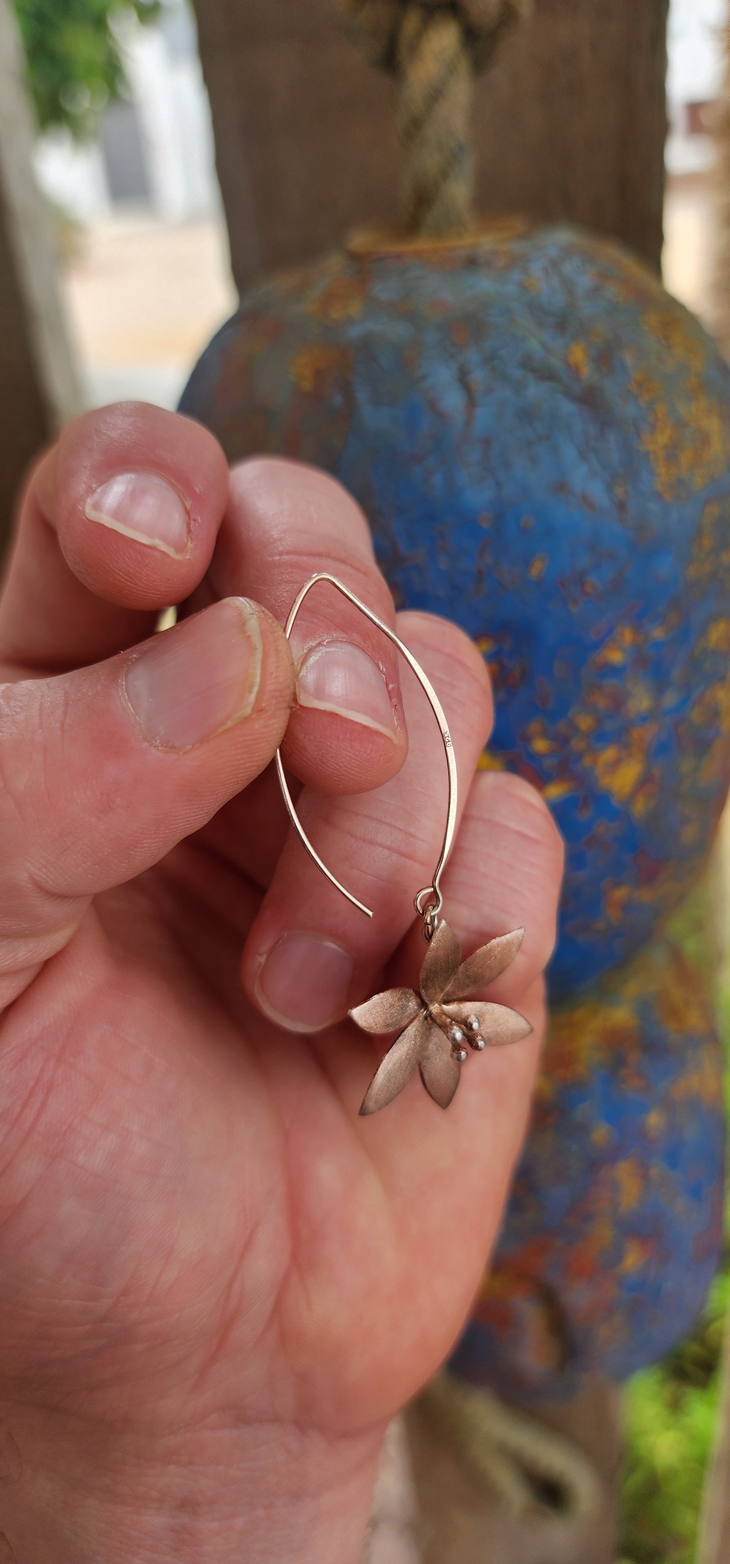 Crafted in sterling silver and finished with a subtle rose-gold wash, these flower drop earrings glow with a warm, romantic hue rather than a high-shine flash.