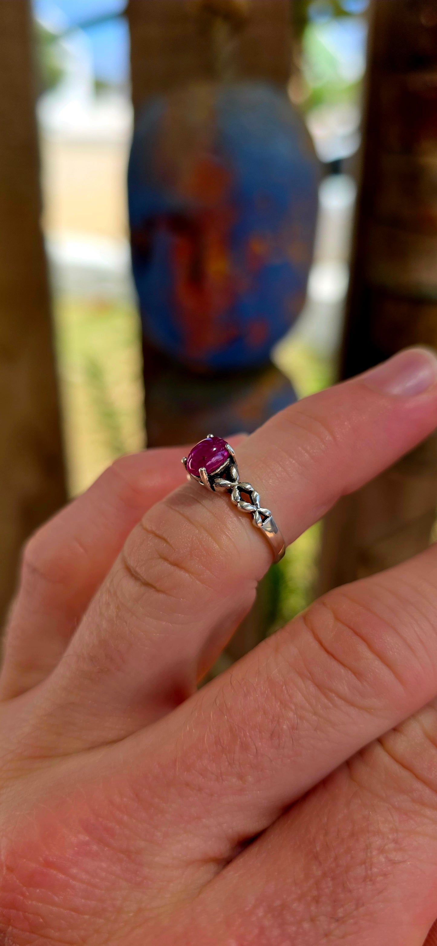 This beautiful sterling silver solitaire-style ring features a glowing oval-cut ruby cabochon, prong-set proudly at the centre