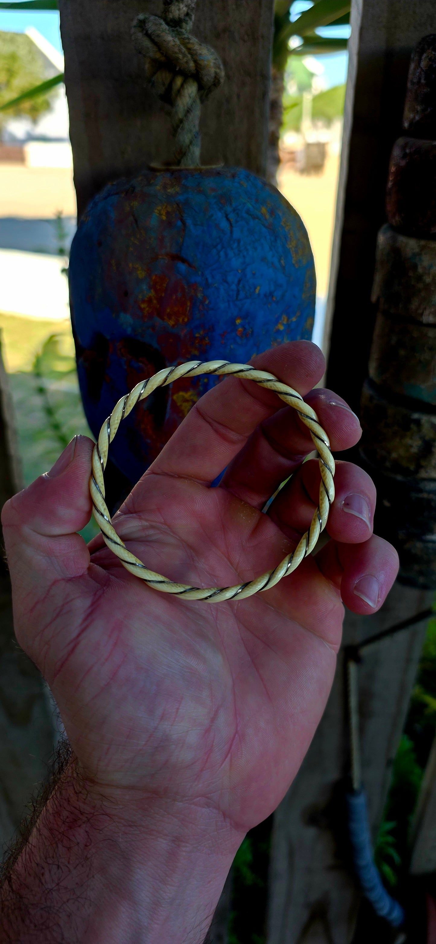 A beautiful antique hand-carved ivory bangle, crafted in a graceful twisted rope / swirl pattern and delicately wrapped with fine sterling silver wire that spirals along the entire circumference of the bracelet.