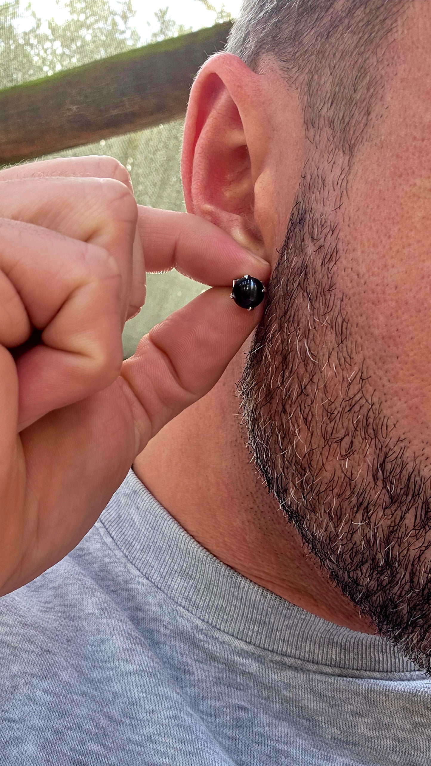 Unisex pair of sterling silver stud earrings with luxurious rhodium plating for a bright tarnish-resistant finish, each prong set with a genuine rare black star diopside cabochon gemstone.