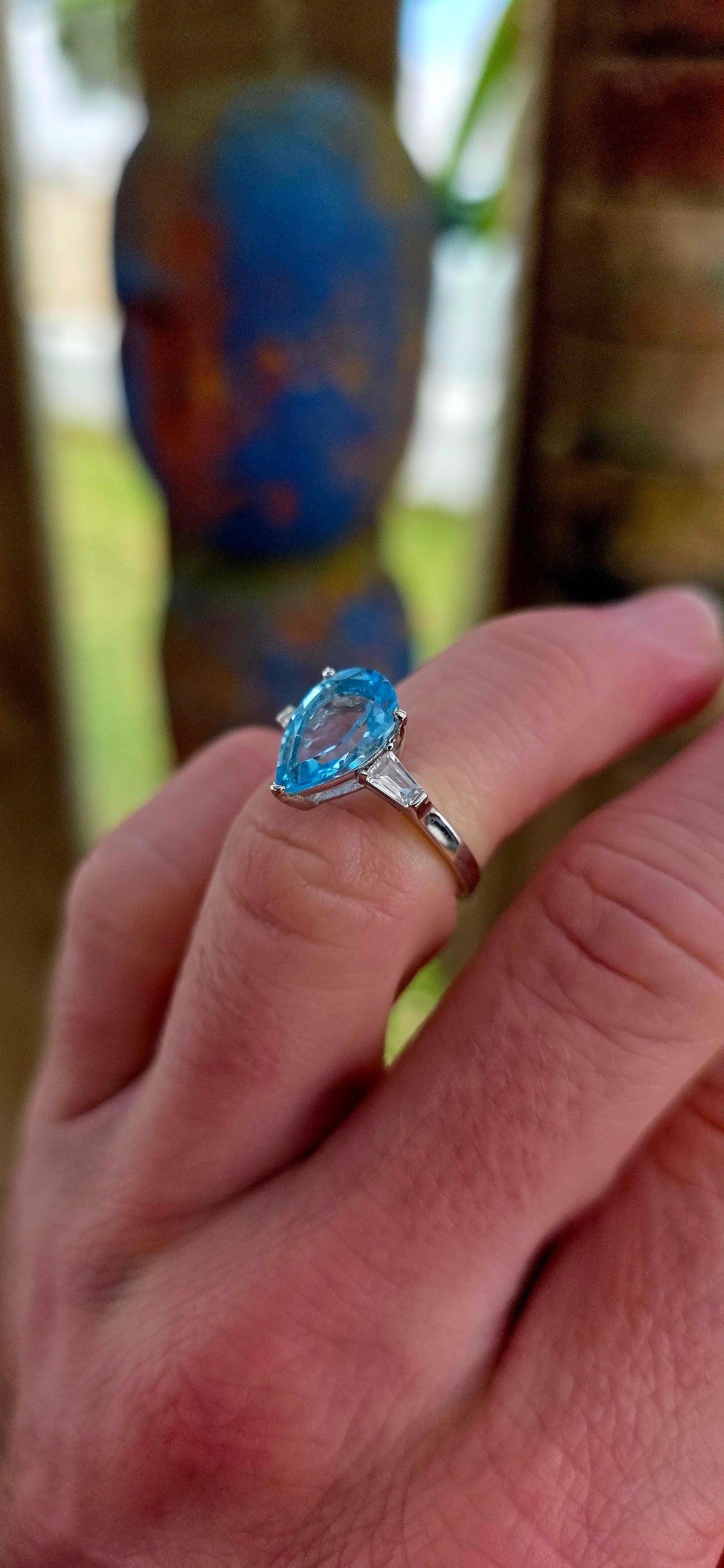 This elegant Art Deco revival trilogy ring is crafted in sterling silver and crowned with a generously sized pear-cut Swiss blue topaz in a classic prong setting.