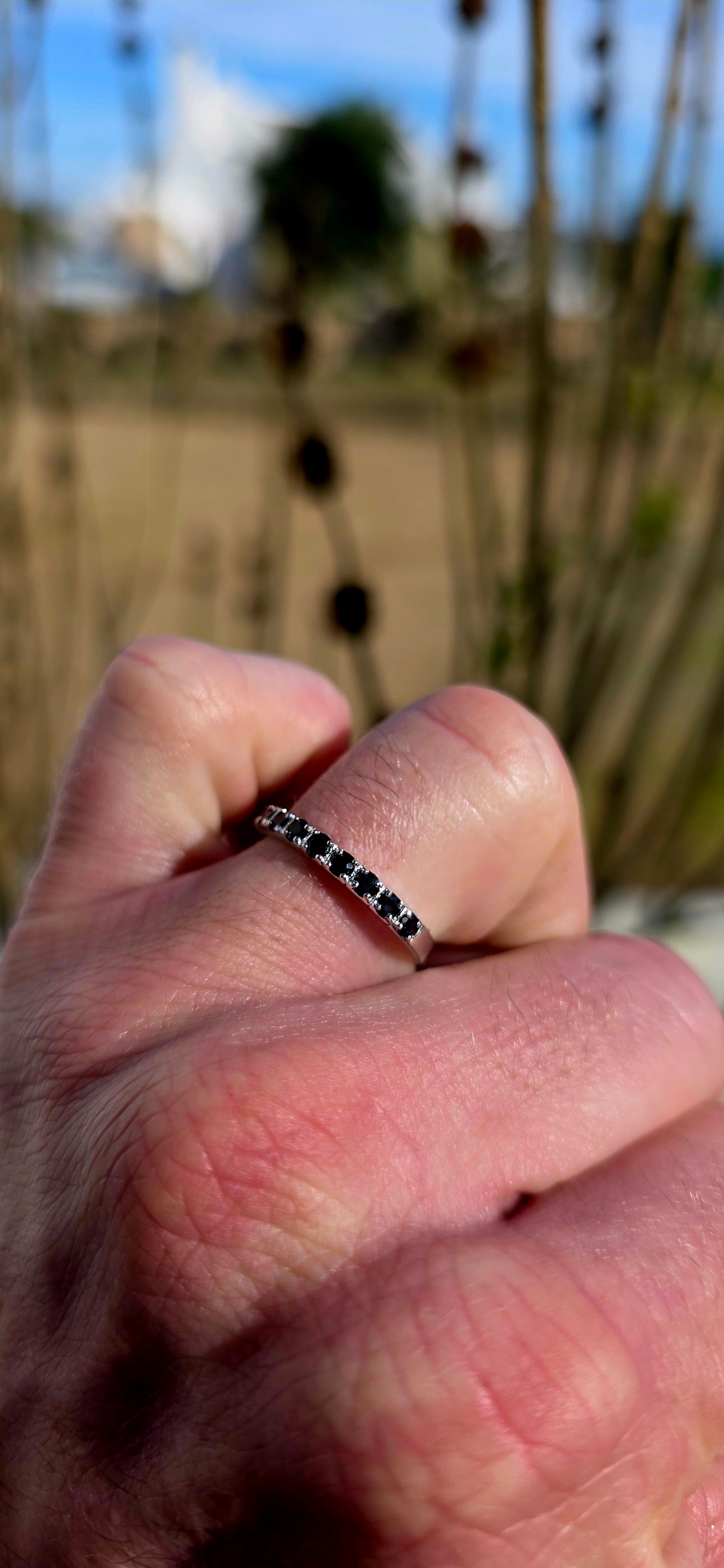 Crafted in sterling silver, this dainty stacking ring is beautifully set with nine round-cut blue sapphires in a delicate combination of prong and flush-style settings.