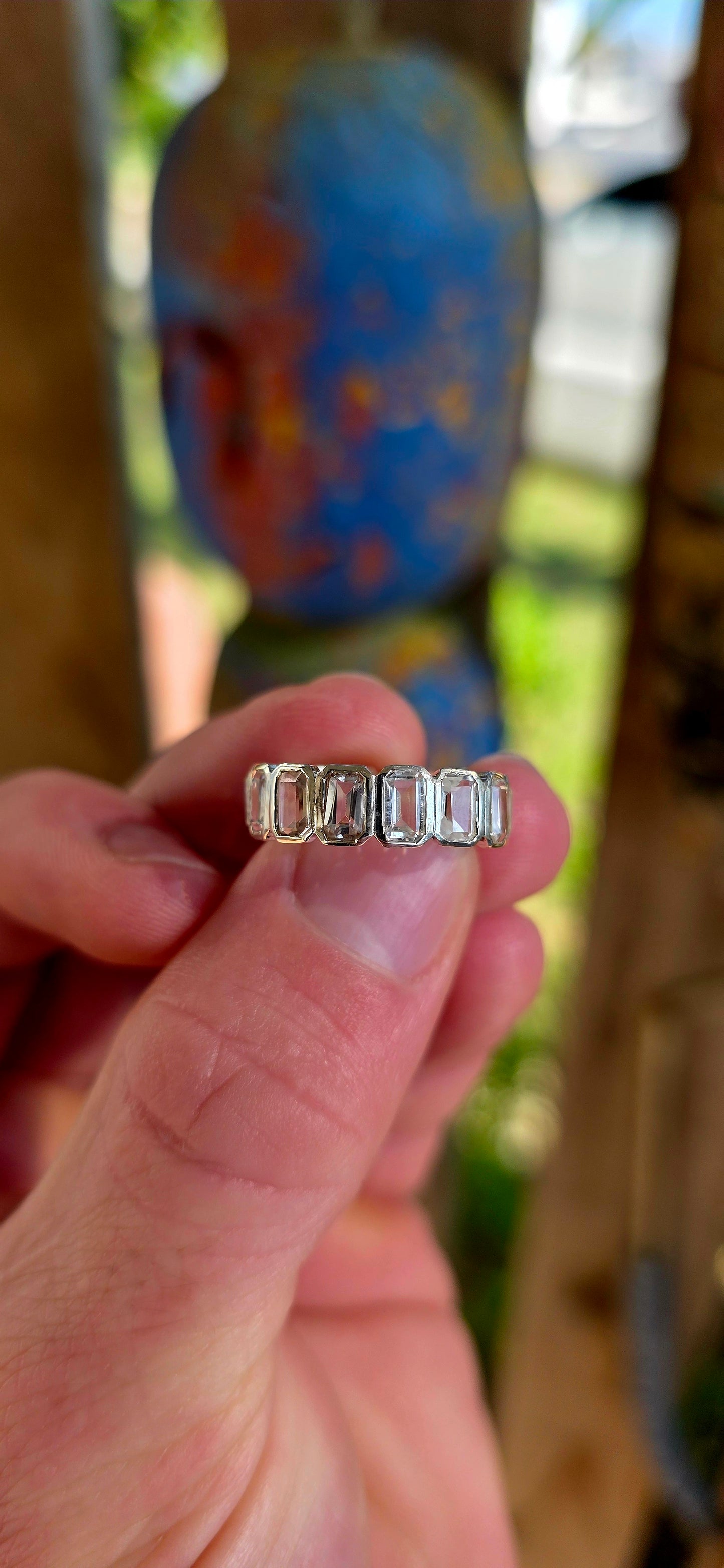 A truly breathtaking sterling silver full eternity ring, shimmering with fourteen emerald-cut white topaz gemstones set continuously all the way around the band in sleek tube settings.