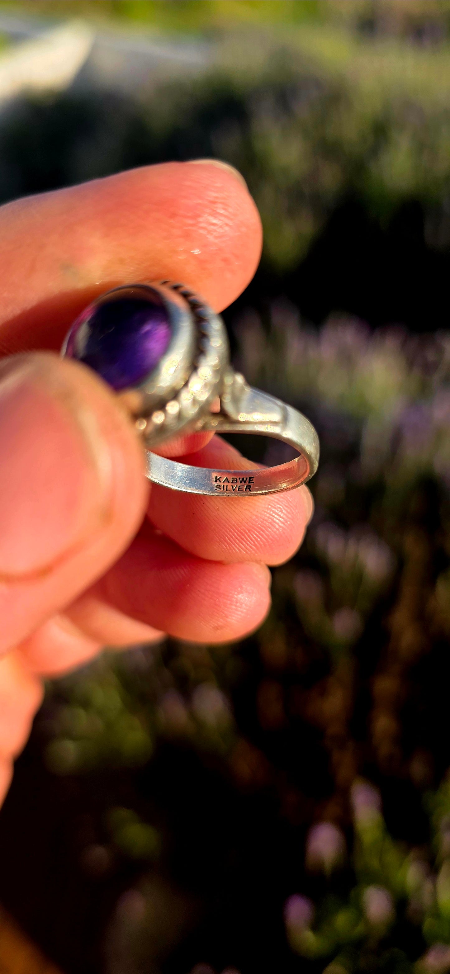 This striking handcrafted Kabwe sterling silver ring features a glowing rounded amethyst cabochon, elegantly tube-set within a beautifully raised and richly textured domed setting.
