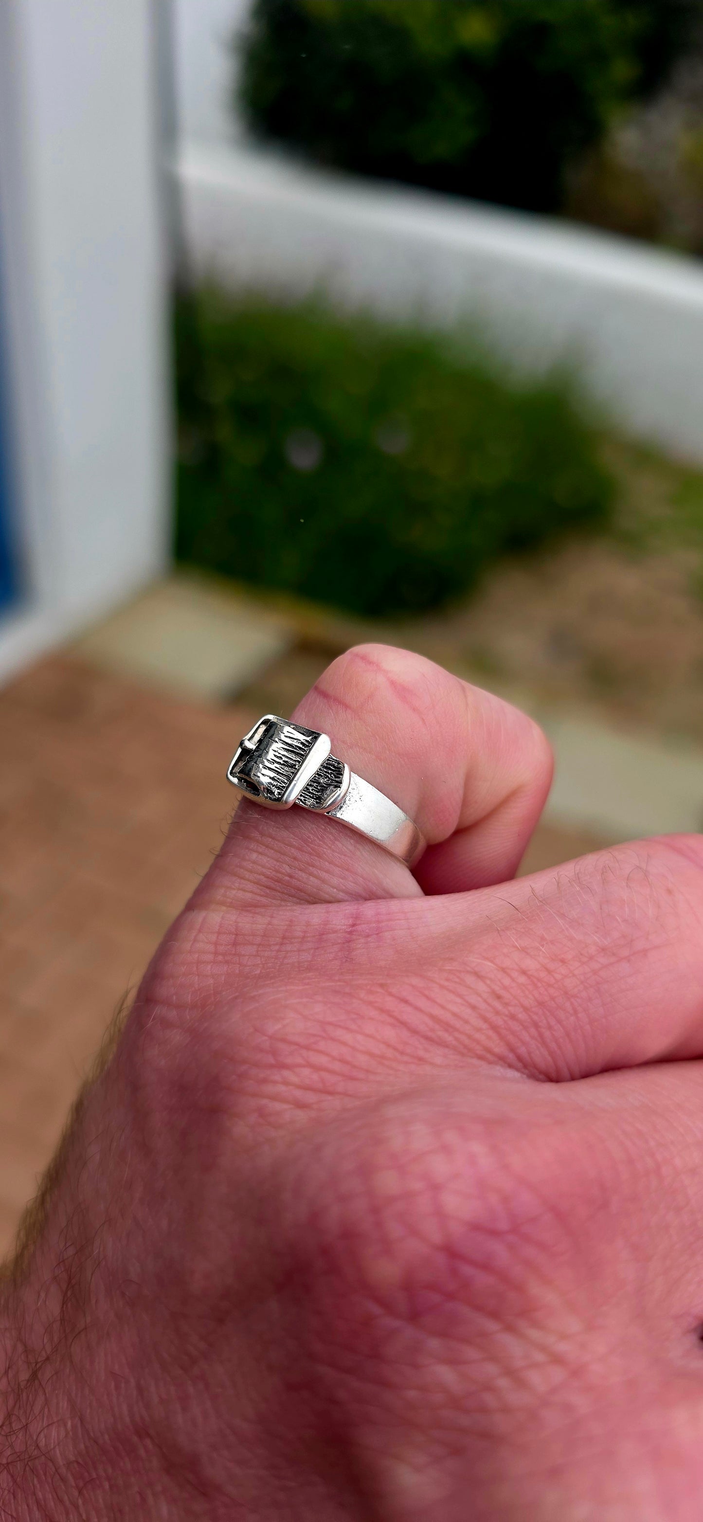A vintage sterling silver Victorian Revival pinky ring, fashioned in the form of a miniature belt and buckle, complete with wonderful textured detailing and a raised buckle across the front.
