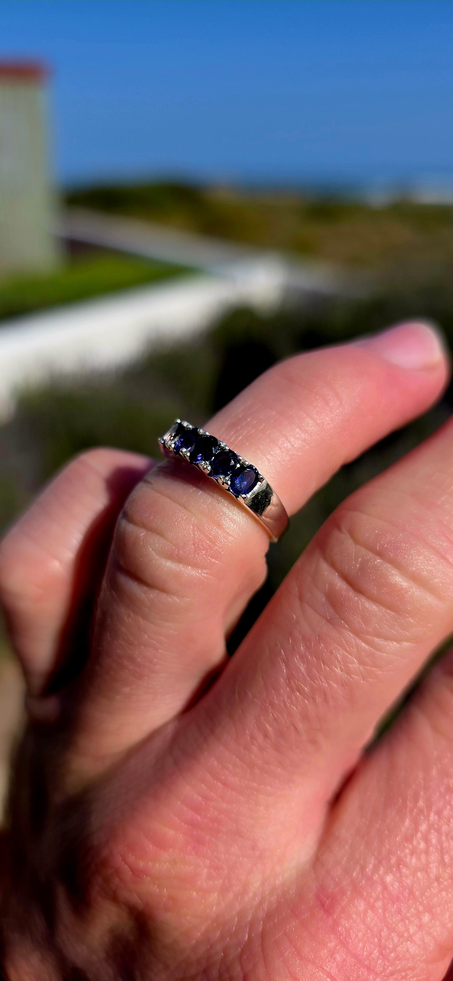 Understated, elegant and wonderfully easy to wear! This sterling silver half-eternity stacking ring is beautifully prong-set across the front with five oval-cut natural iolite gemstones.