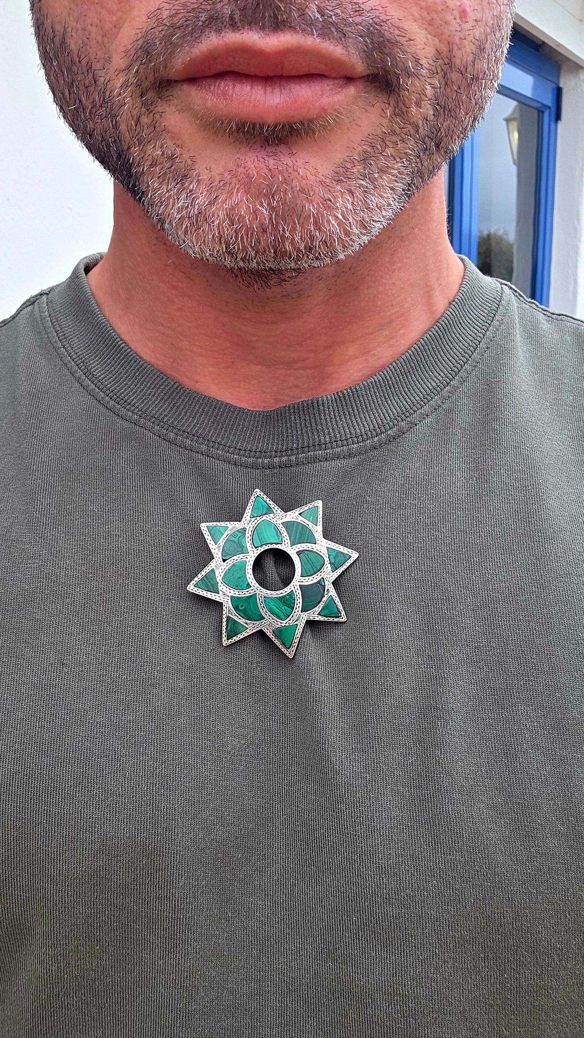 Dating to approximately the 1870s, this generously sized antique brooch is crafted in sterling silver and beautifully inlaid with individual sections of richly patterned natural malachite.