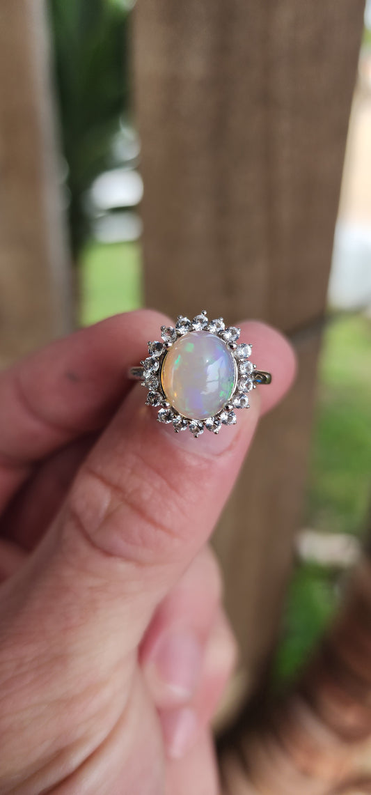 Sterling Silver ,Ethiopian Welo Opal and Clear CZ Gemstone dress Ring .The lovely and generous in size Opal Cabochon has been claw set in an Sparkly Round CZ Haló border.