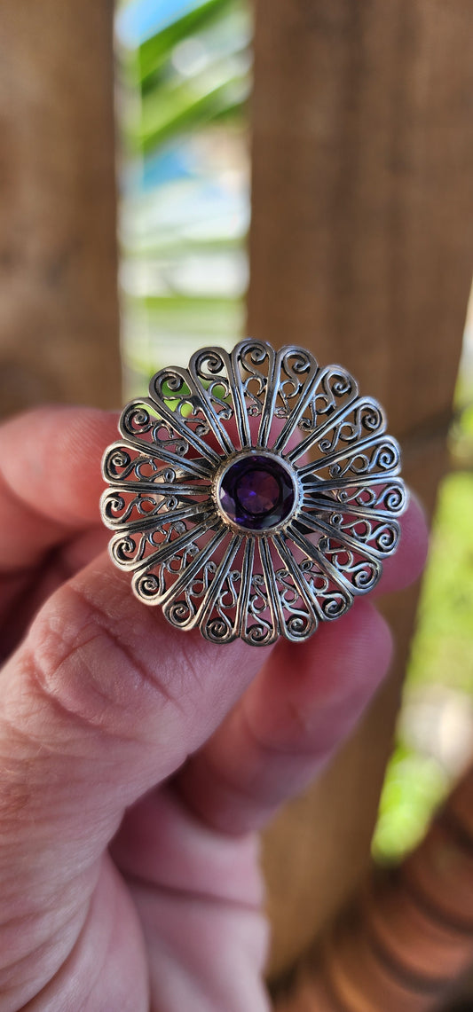 Sterling Silver and Amethyst openwork Floral Coktail/dress ring.
A Sparkling Purple Amethyst forms the center of a large statement flower. The intricate petals offer an eye-catching allure.