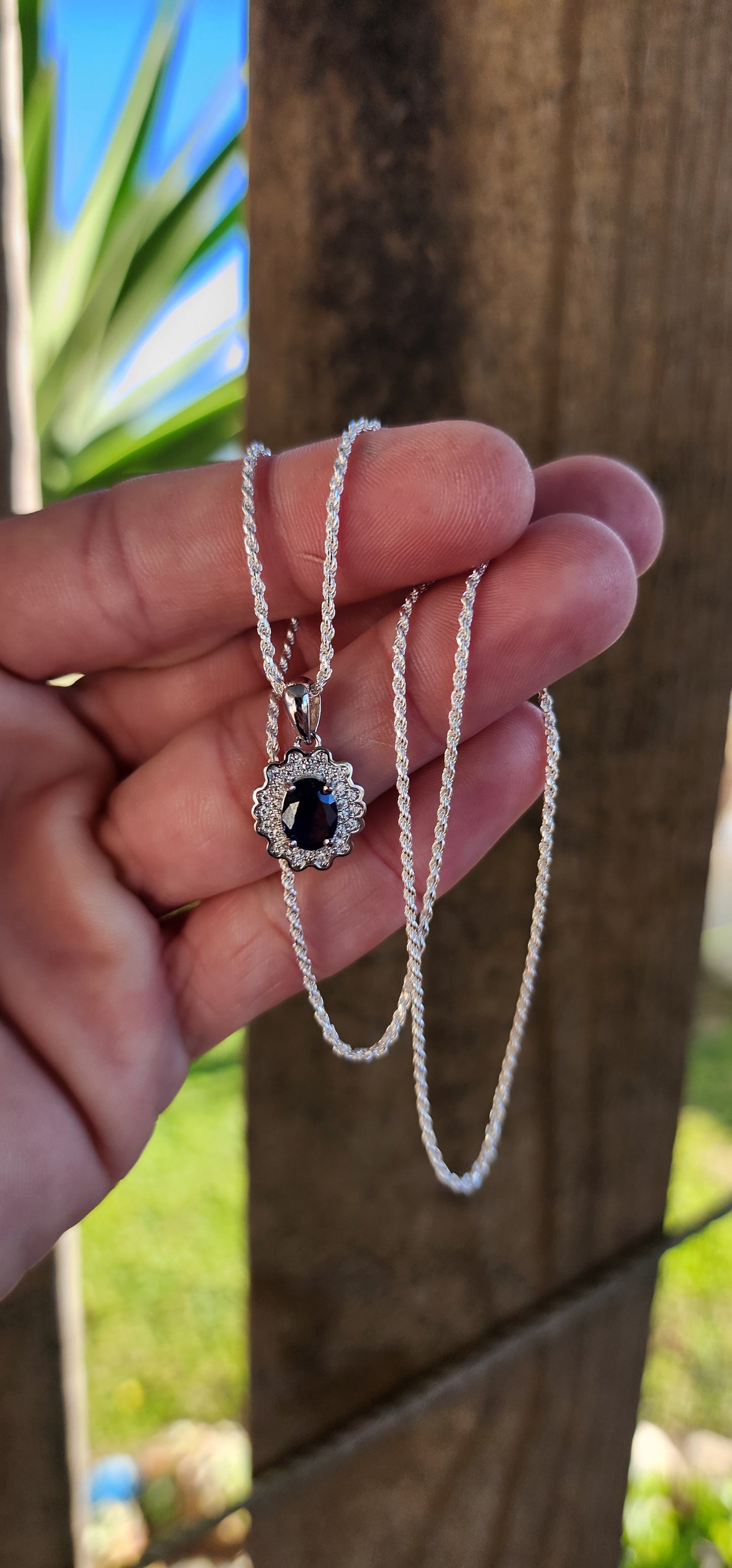 The Birthstone pendant on chain: This showy Natural Oval cut Sapphire Gemstone pendant is enhanced by a flowery Halo of sparkly CZ Gemstones to give you just the the boost you need for that busy work day or for that casual evening out.