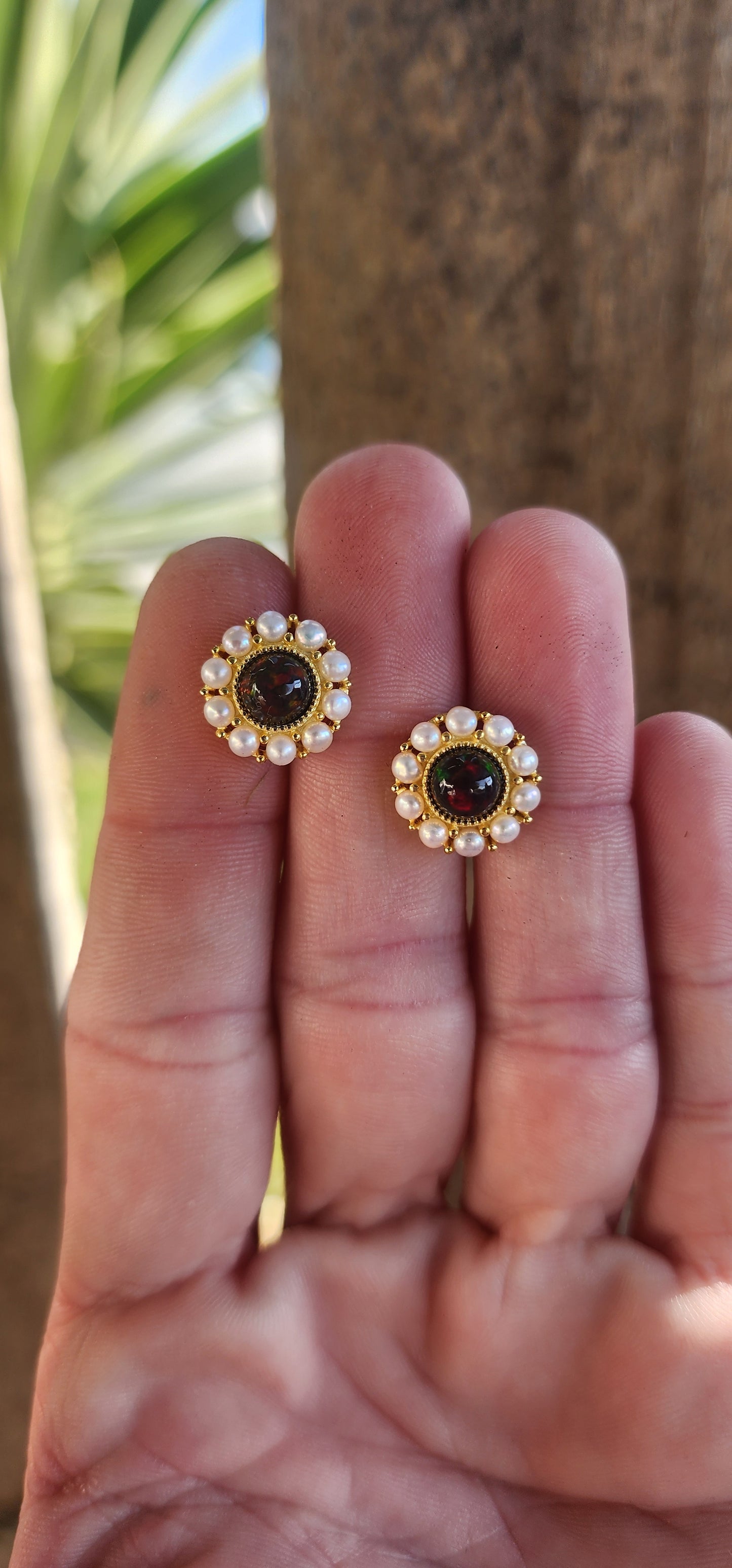 A glowing pair of Sterling Silver with Yellow Gold plating Halo Earstuds composed of Ethiopian Black Opals and Seed Pearls in a concentrical layout. Each piece features a Black Ethiopian Opal in the centre, surrounded by a Halo of Cultured Seed Pearls.