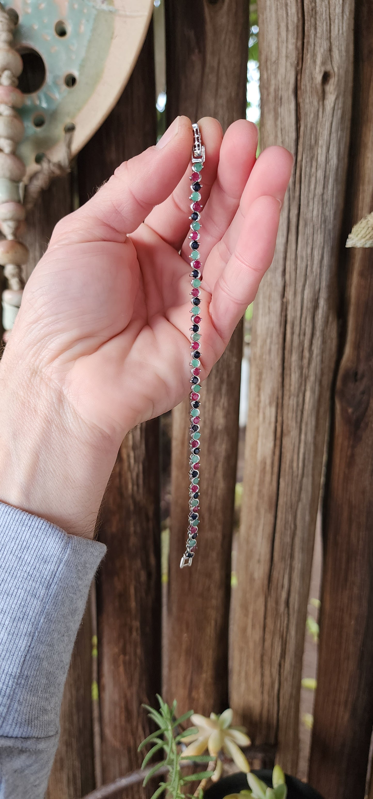 Classical beauty!This alluring Tennis bracelet is crafted in lustrous Sterling Silver and features 48x claw/tube set Natural Round Cut Rubies,Emeralds and Sapphire Gemstones in a curved wave design.Fitted with a ornate pierced clip clasp.