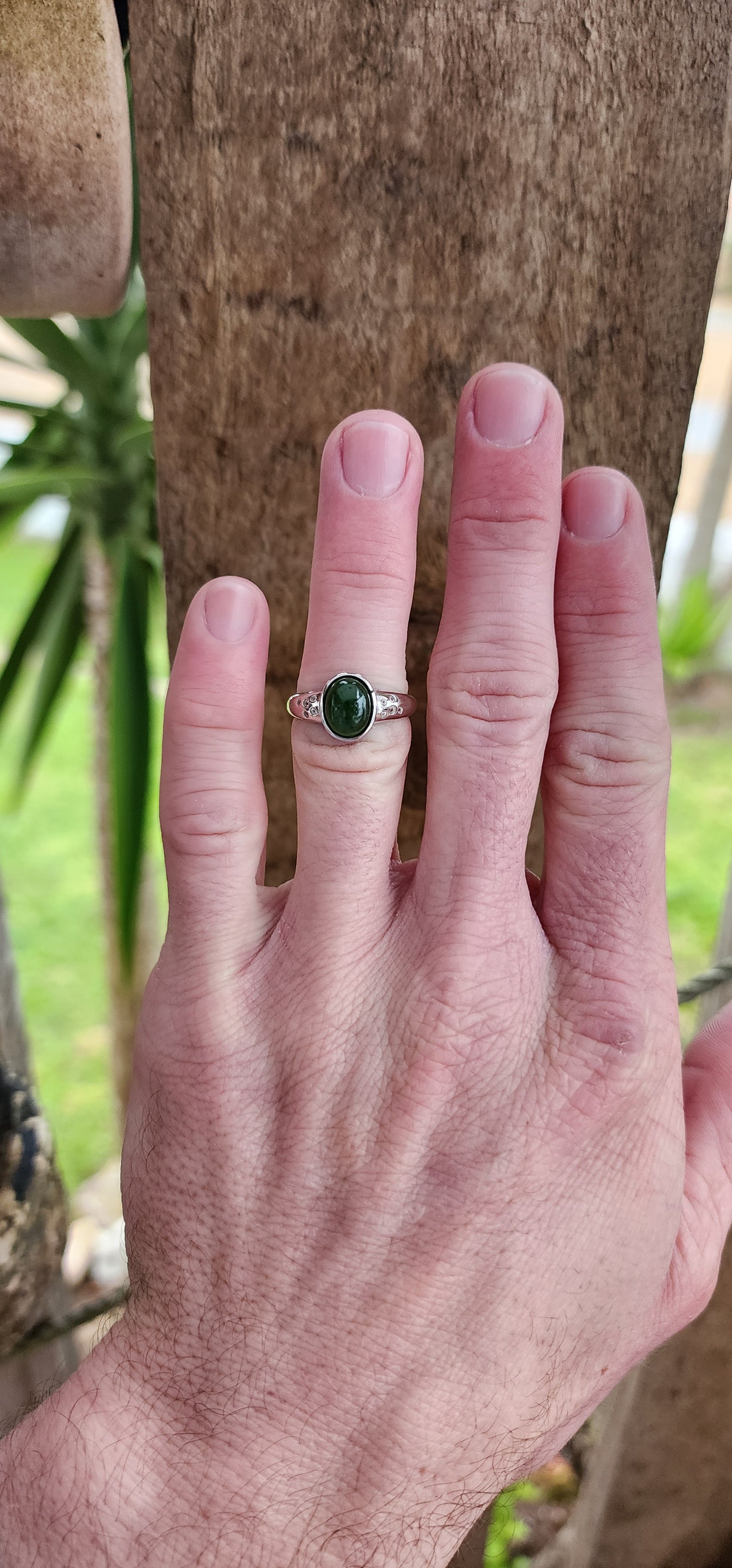 Sterling Silver Trilogy style ring bezel/tube set with a Oval shaped Green Nephrite Jade Cabochon in the centre and furthermore flush set with 5 x small CZ Gemstones on either side of the Jade Cabochon.